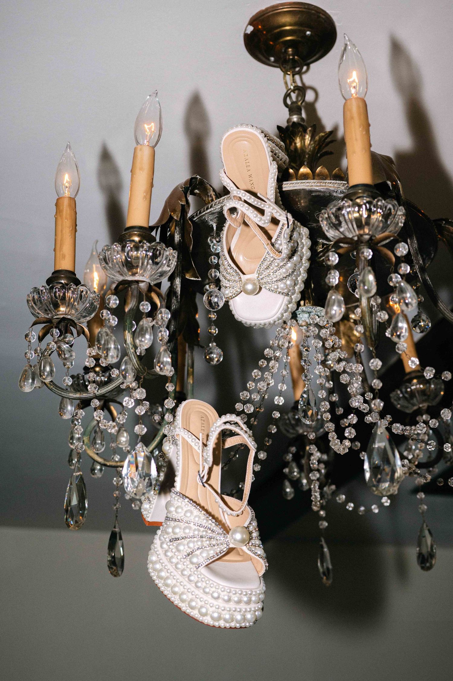 Crystal chandelier adorned with an elegant white bridal shoe.