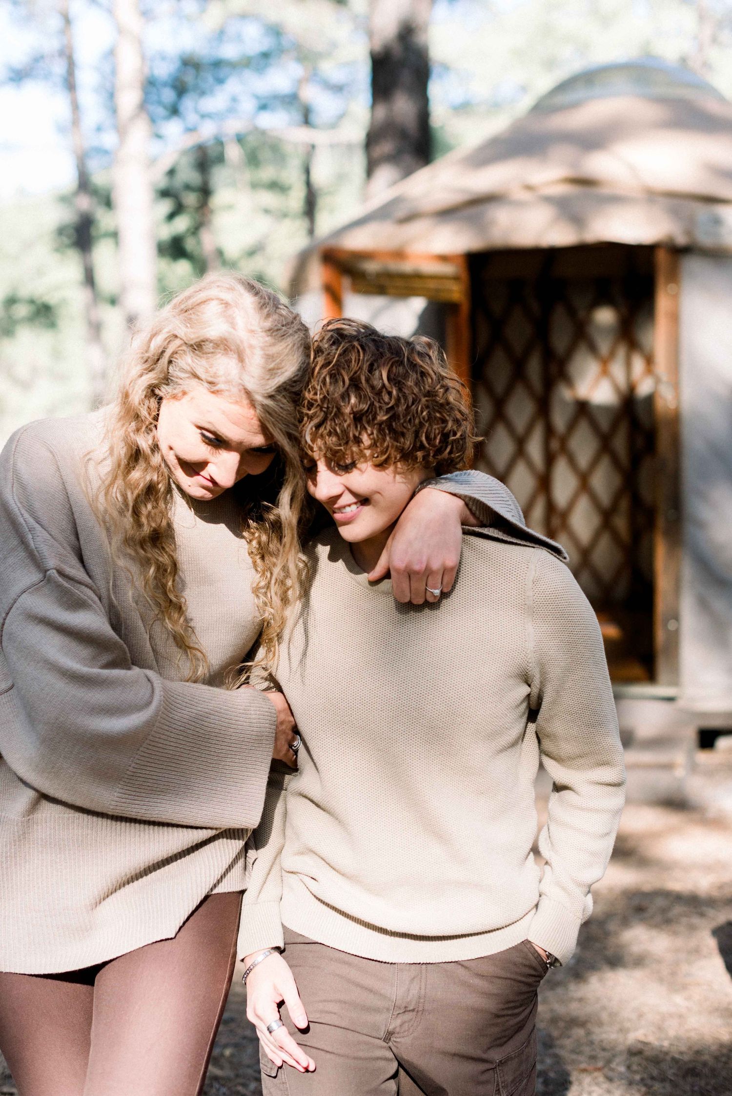 Candid outdoor portrait of couple in matching beige sweaters.