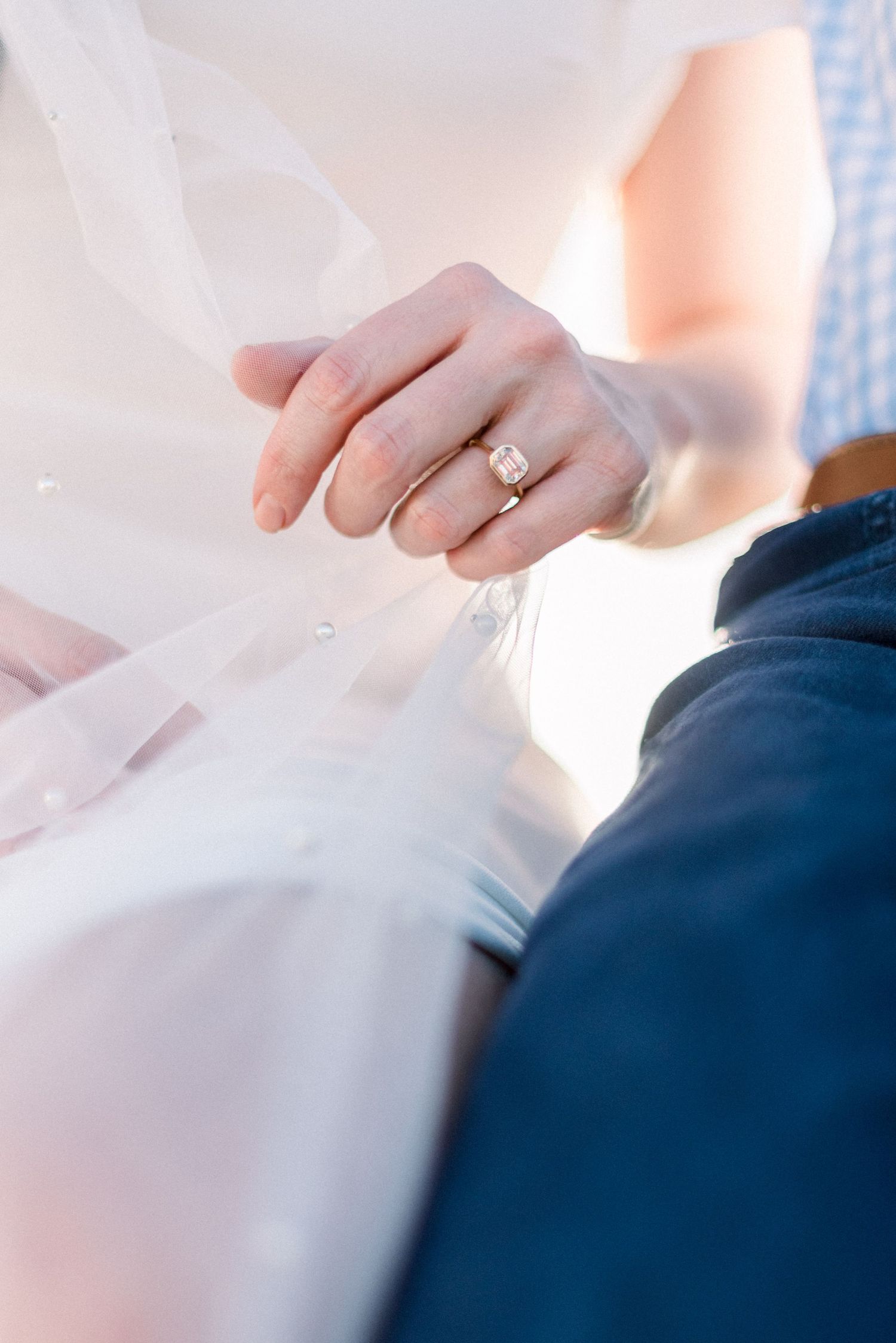 Close-up shot of an engagement ring with soft natural lighting and flowing fabric details.