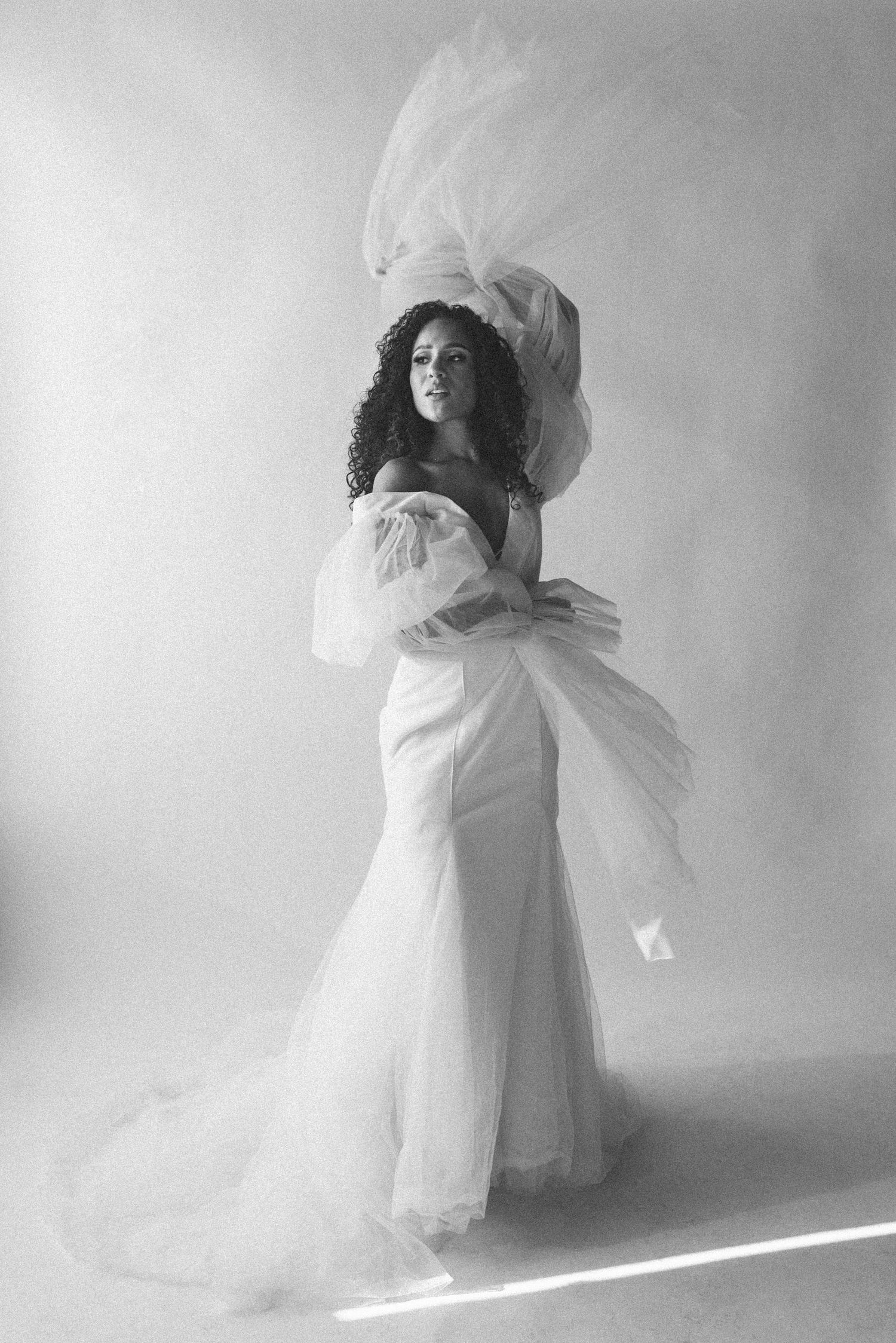 Black and white portrait of bride in flowing wedding dress with dramatic movement.