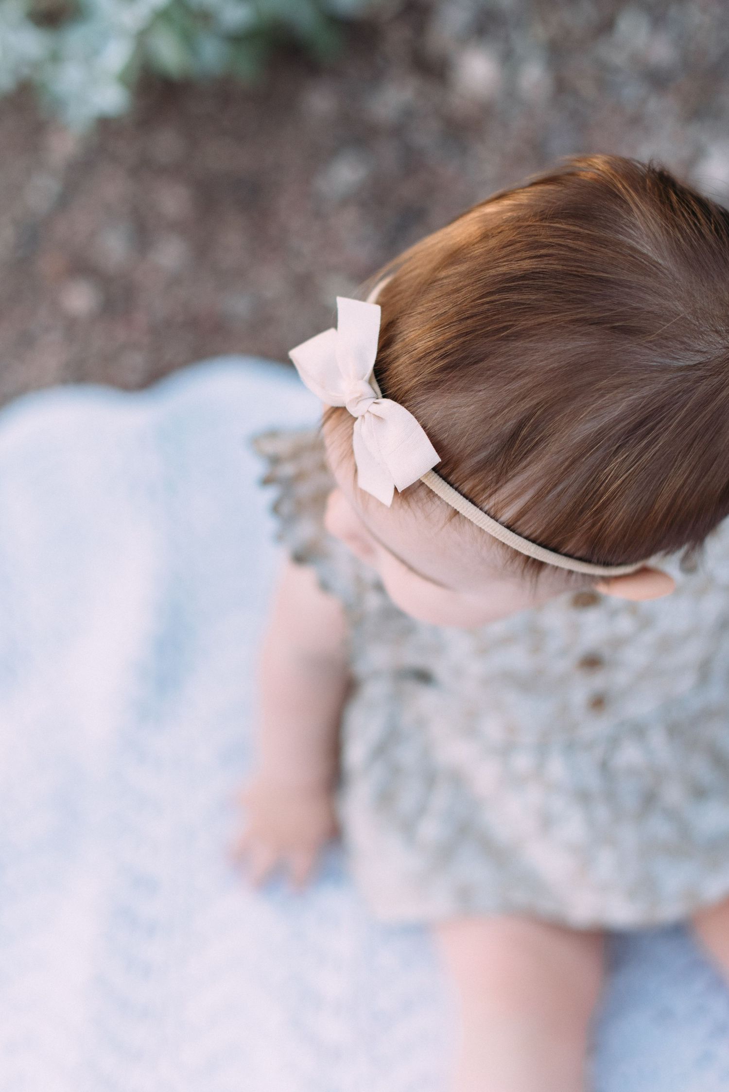Close-up view of a light pink bow headband accessory in soft natural lighting.