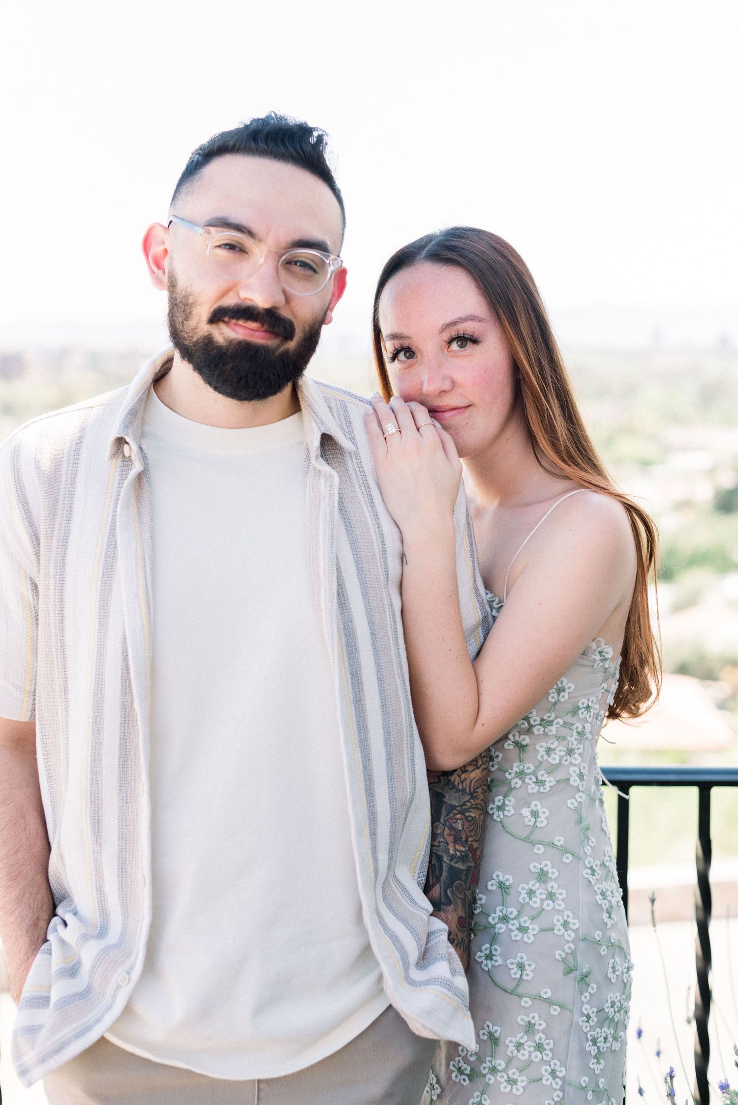 Couple poses together on balcony in casual spring outfits.