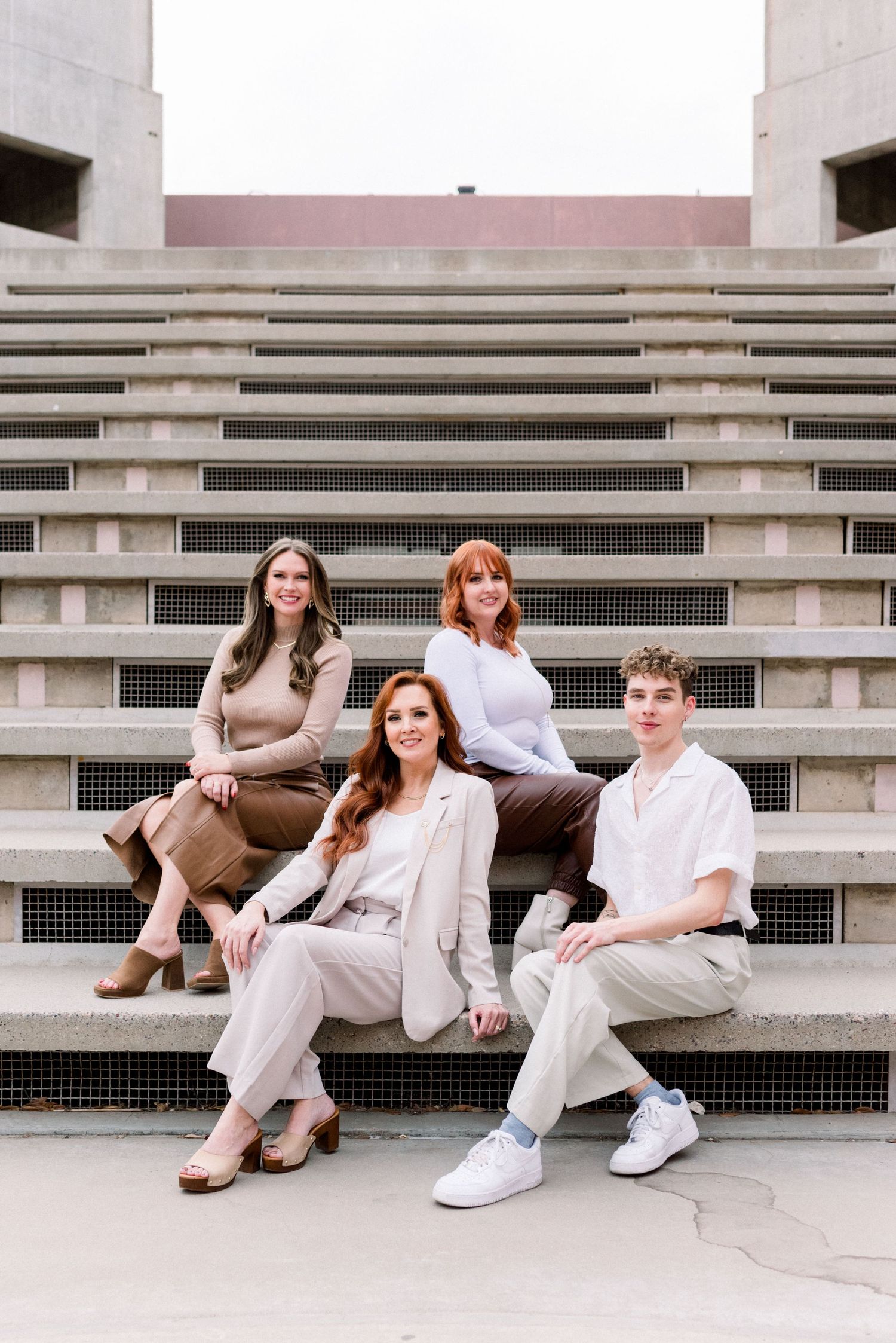 Fashion group portrait on architectural concrete steps with industrial design elements.