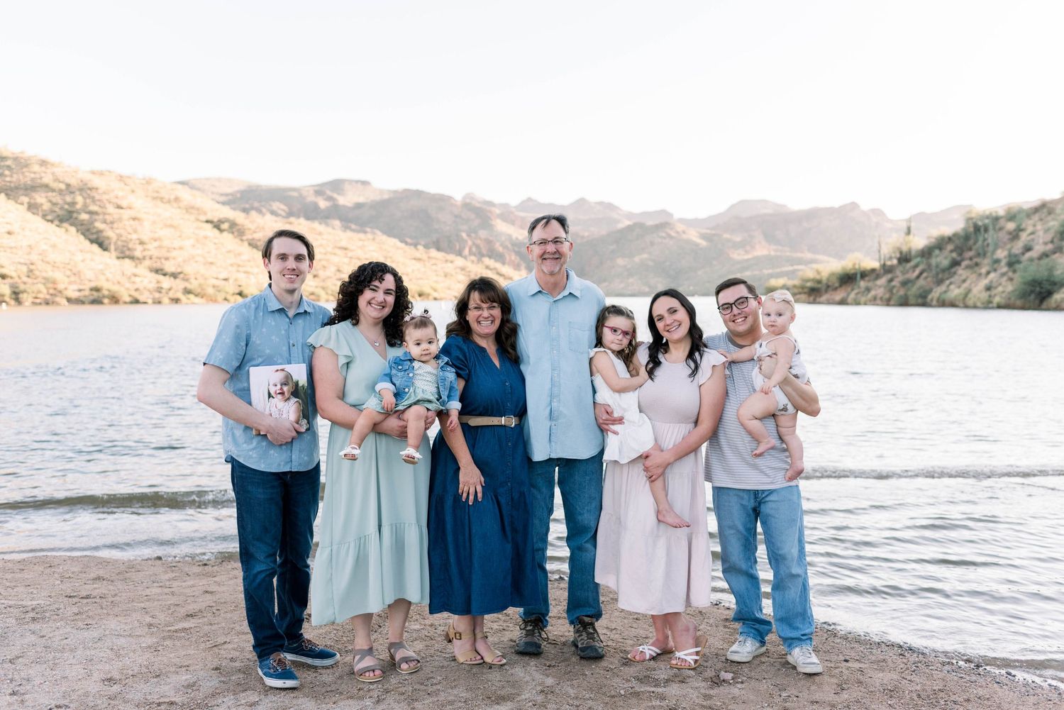 A series of coordinated family portraits taken at sunset on a beach with mountains in the background.
