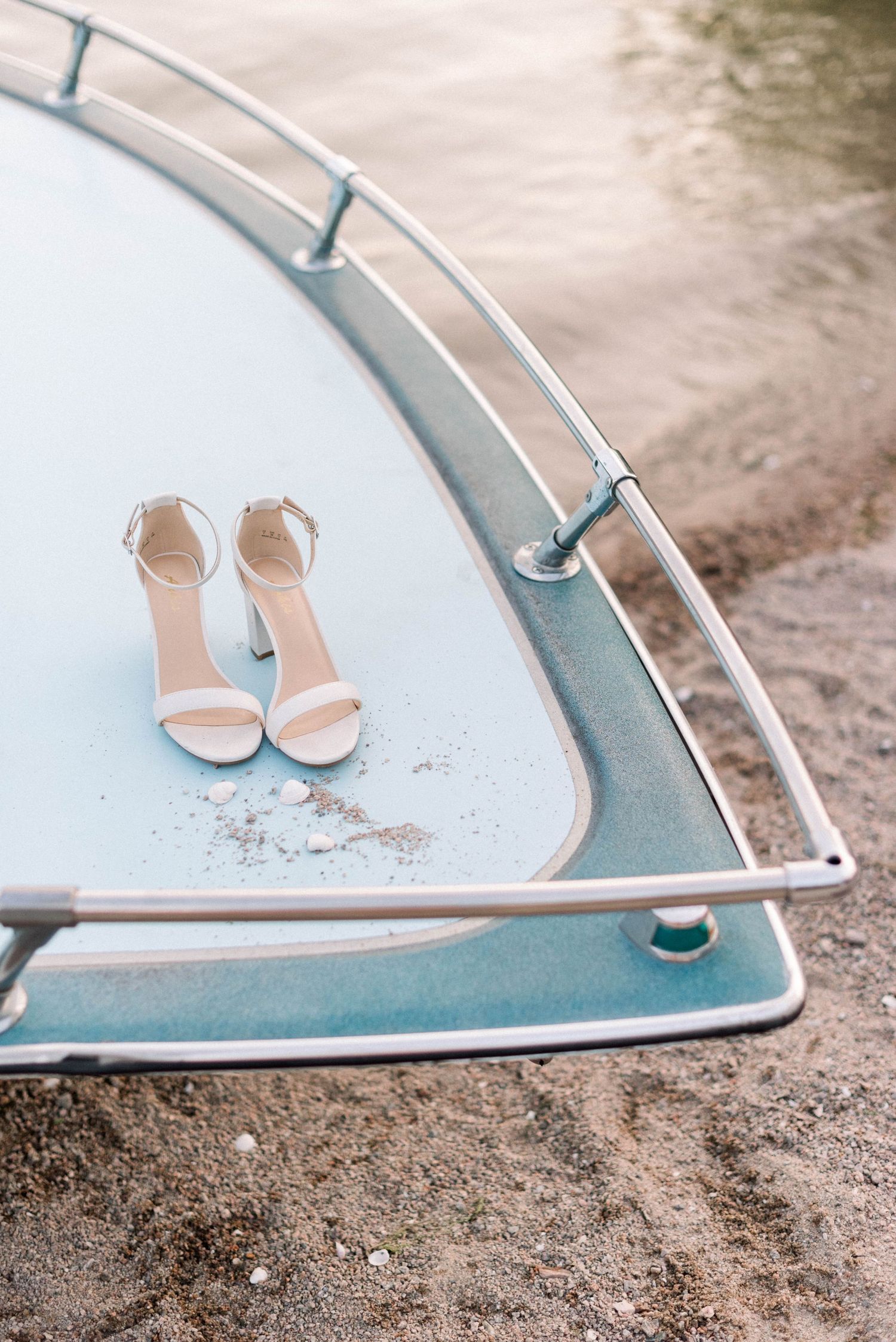 Elegant white bridal sandals placed on a vintage blue surface.