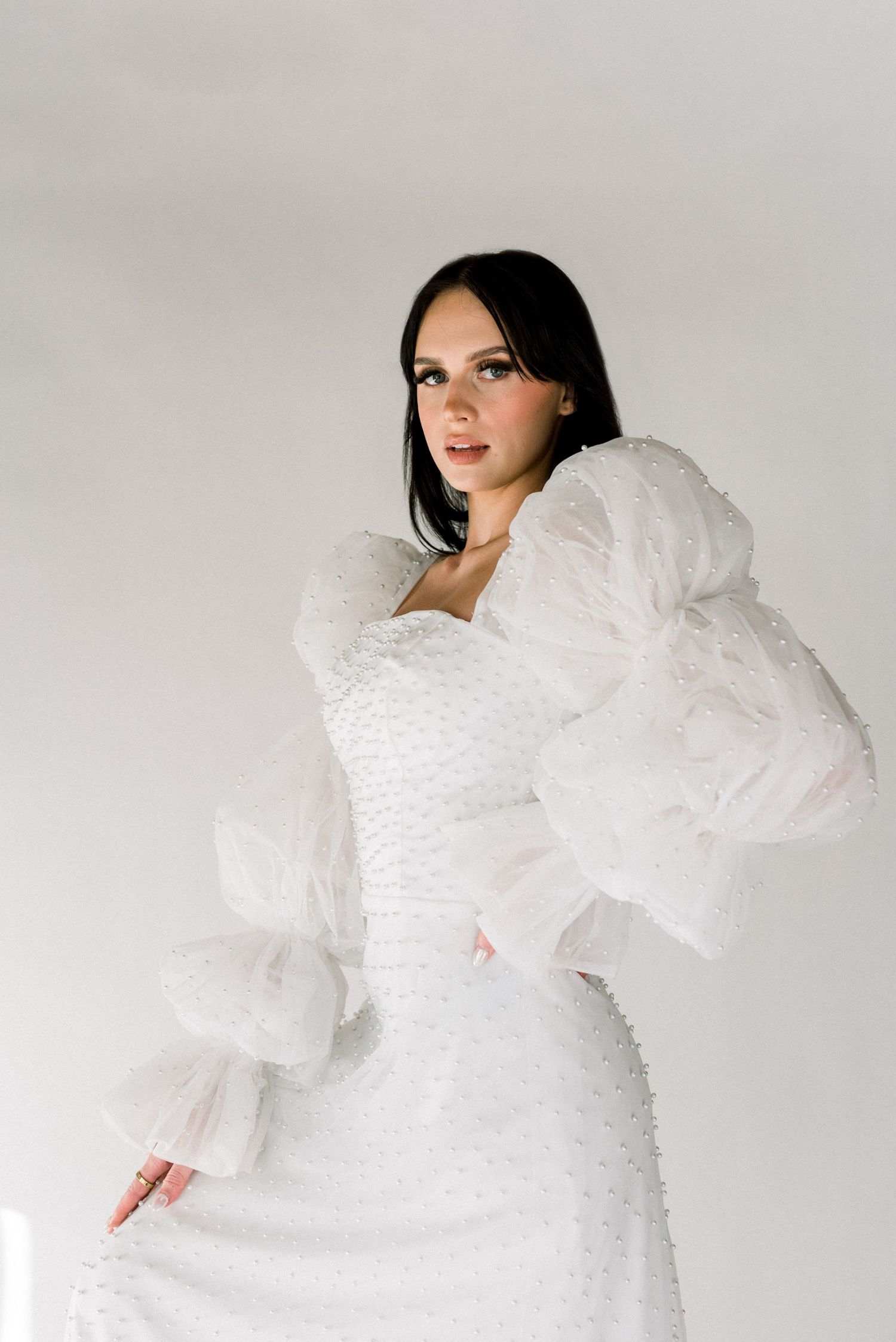 Elegant bridal portrait featuring structured white gown with dramatic puff sleeves.