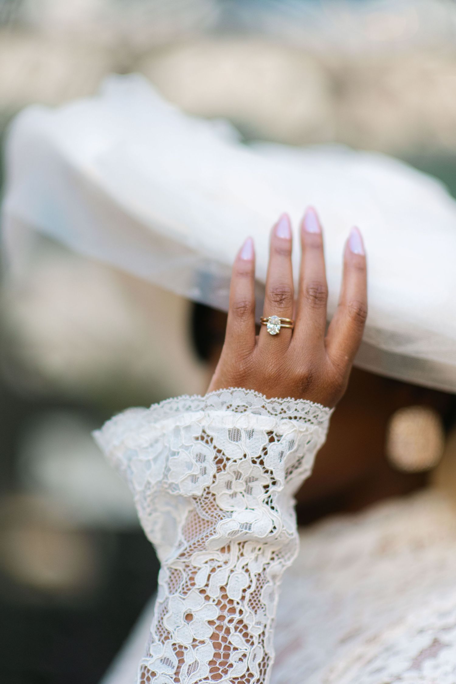 A delicate lace sleeve and wedding ring are showcased in an elegant bridal detail shot.