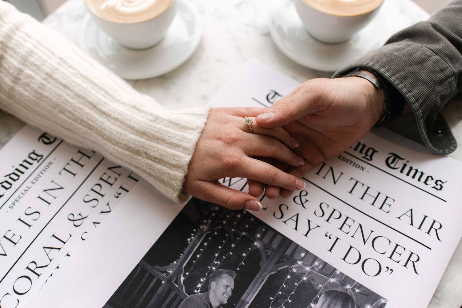 Coffee cups and newspapers arranged on white marble table surface.