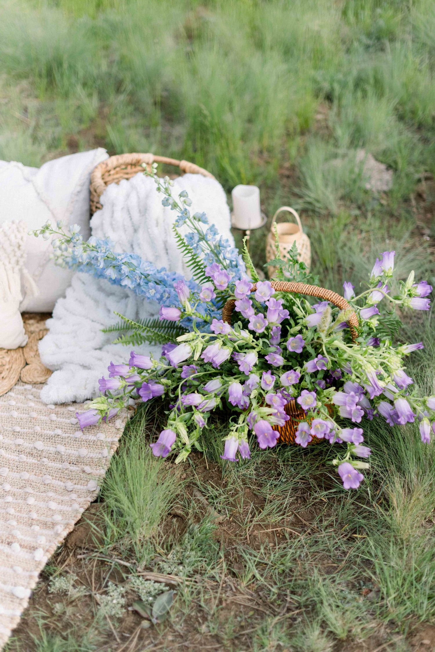 Purple and white wildflower arrangement on a rustic outdoor blanket setting.