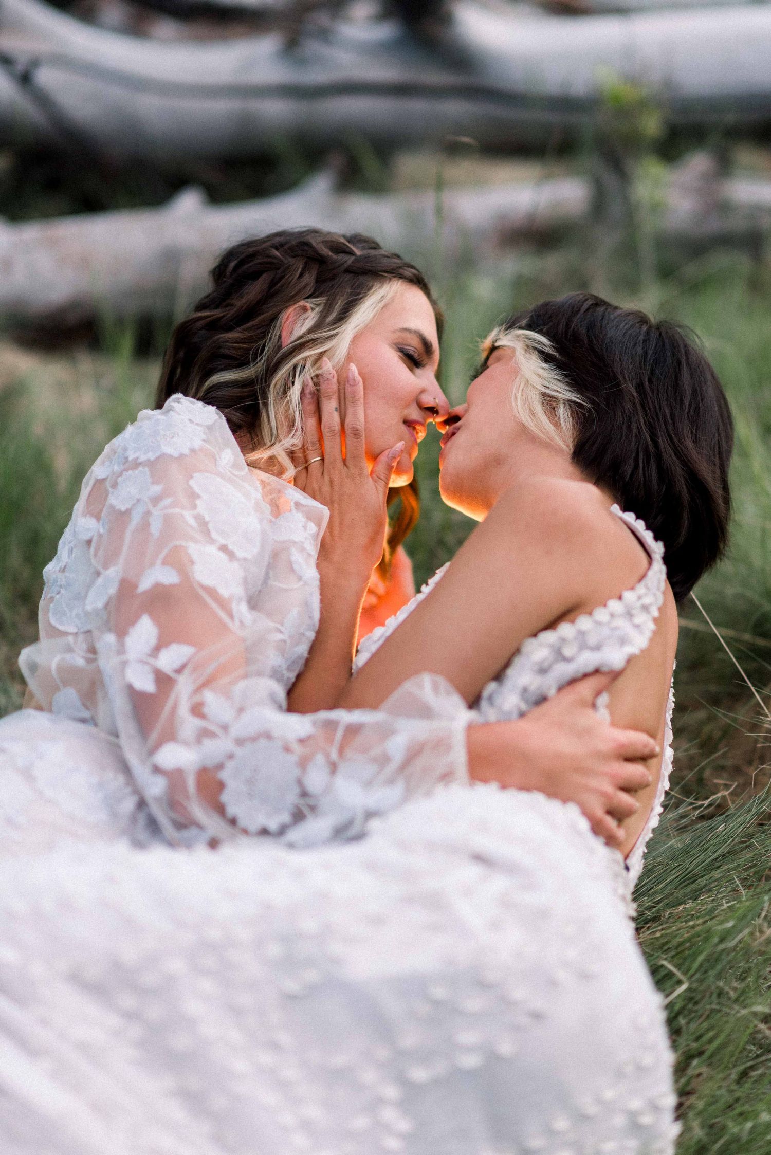 An intimate moment between two people in white lace dresses against a natural backdrop.