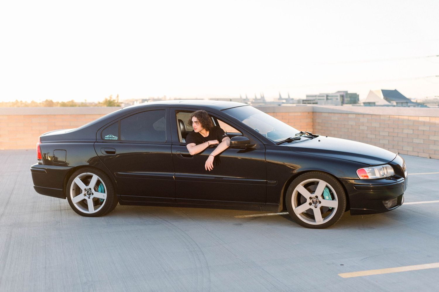 Black sedan car parked in urban setting during golden hour.