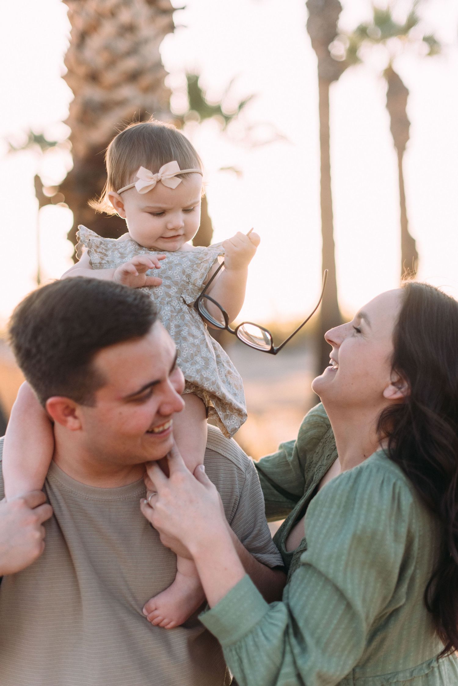 Playful family moment captured during outdoor photoshoot at sunset.