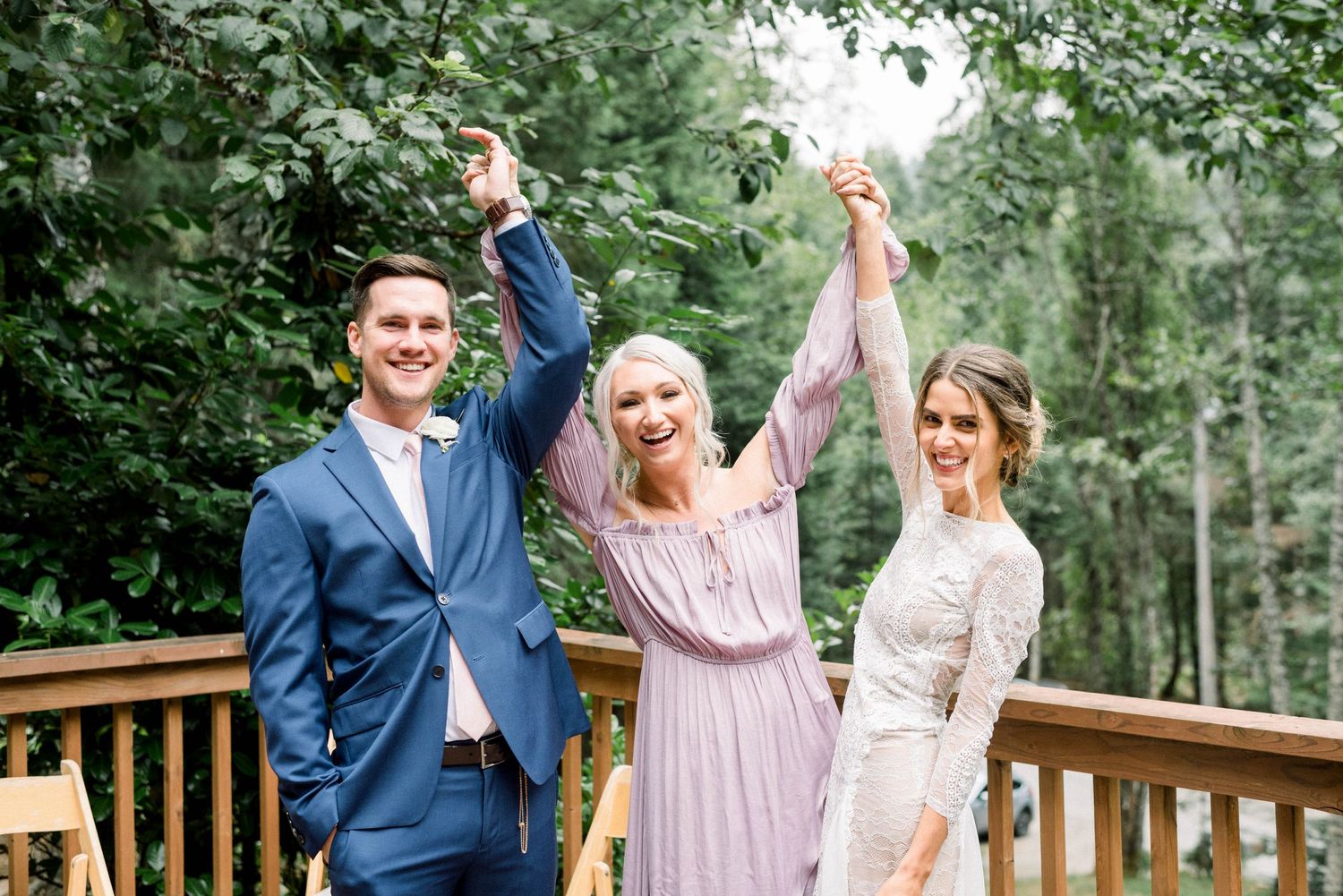 Celebratory moment with guests raising hands in joy on outdoor wedding deck.