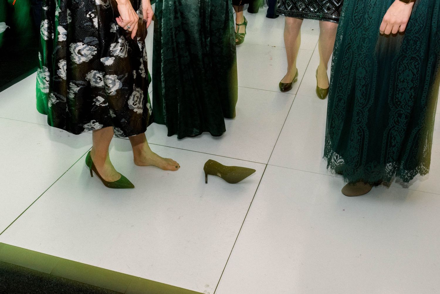 Close-up of wedding guests' formal footwear on white dance floor at reception.