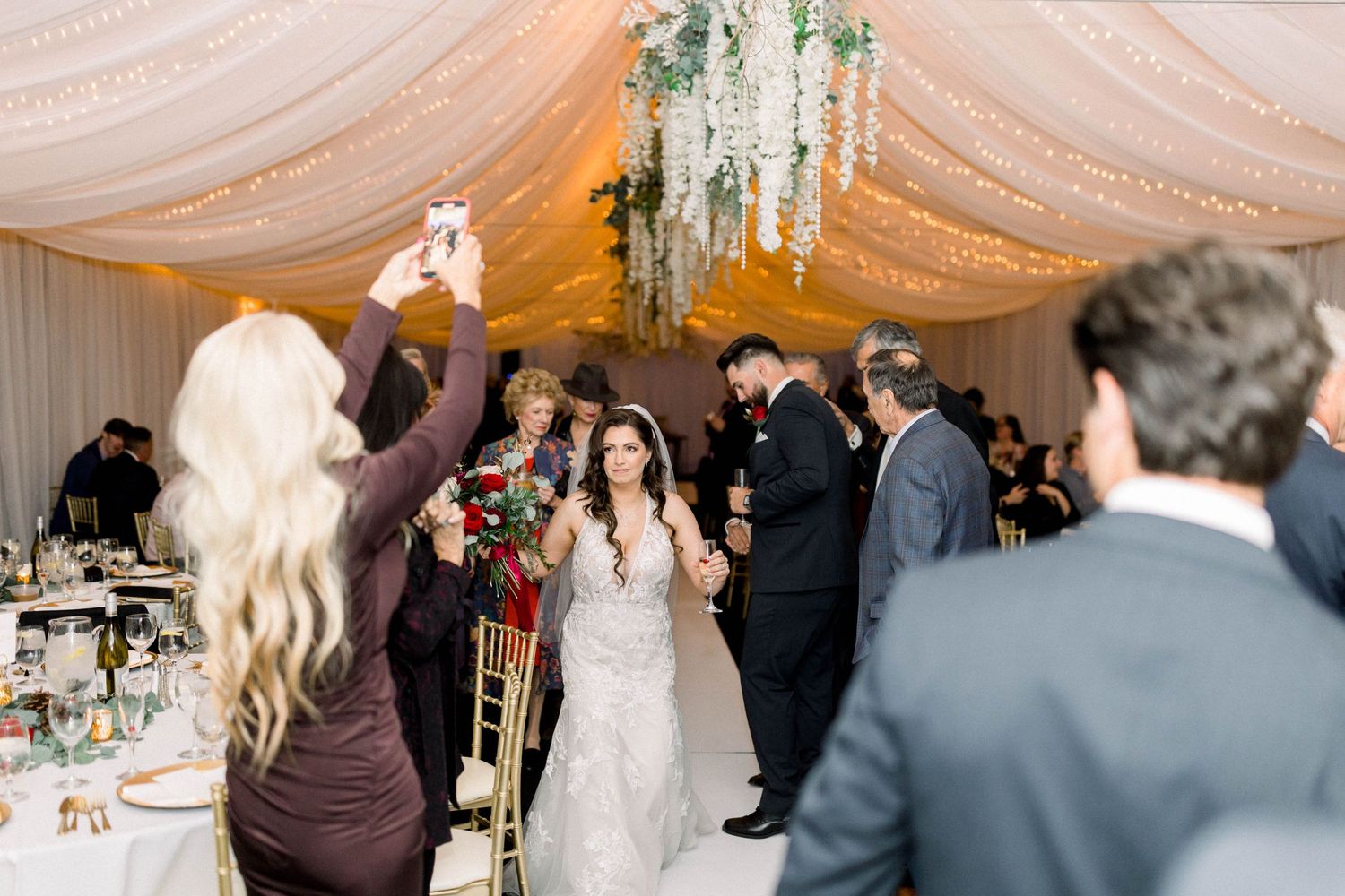 Wedding reception celebration with guests dancing under draped fabric ceiling.