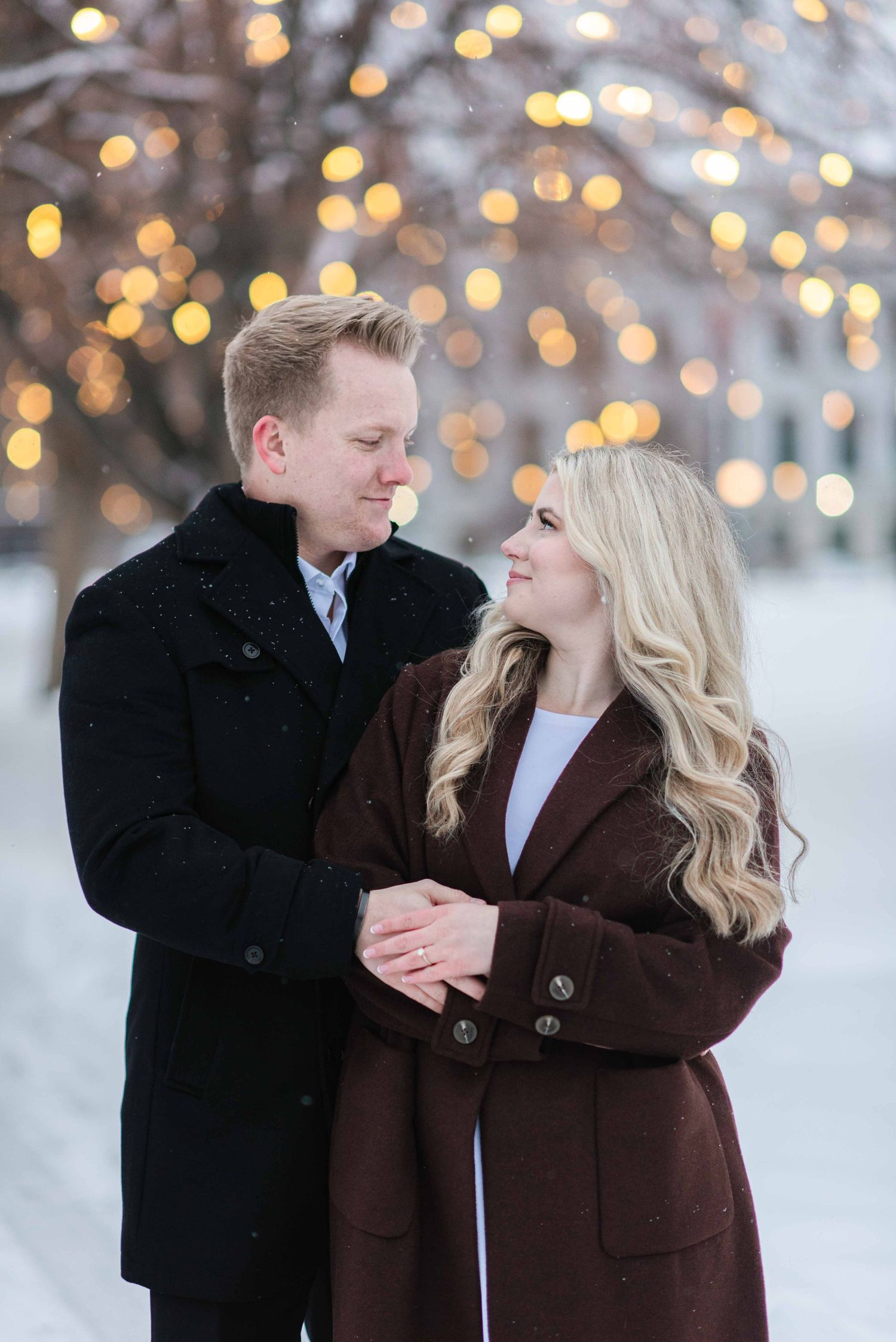A couple shares a tender moment against twinkling winter lights.