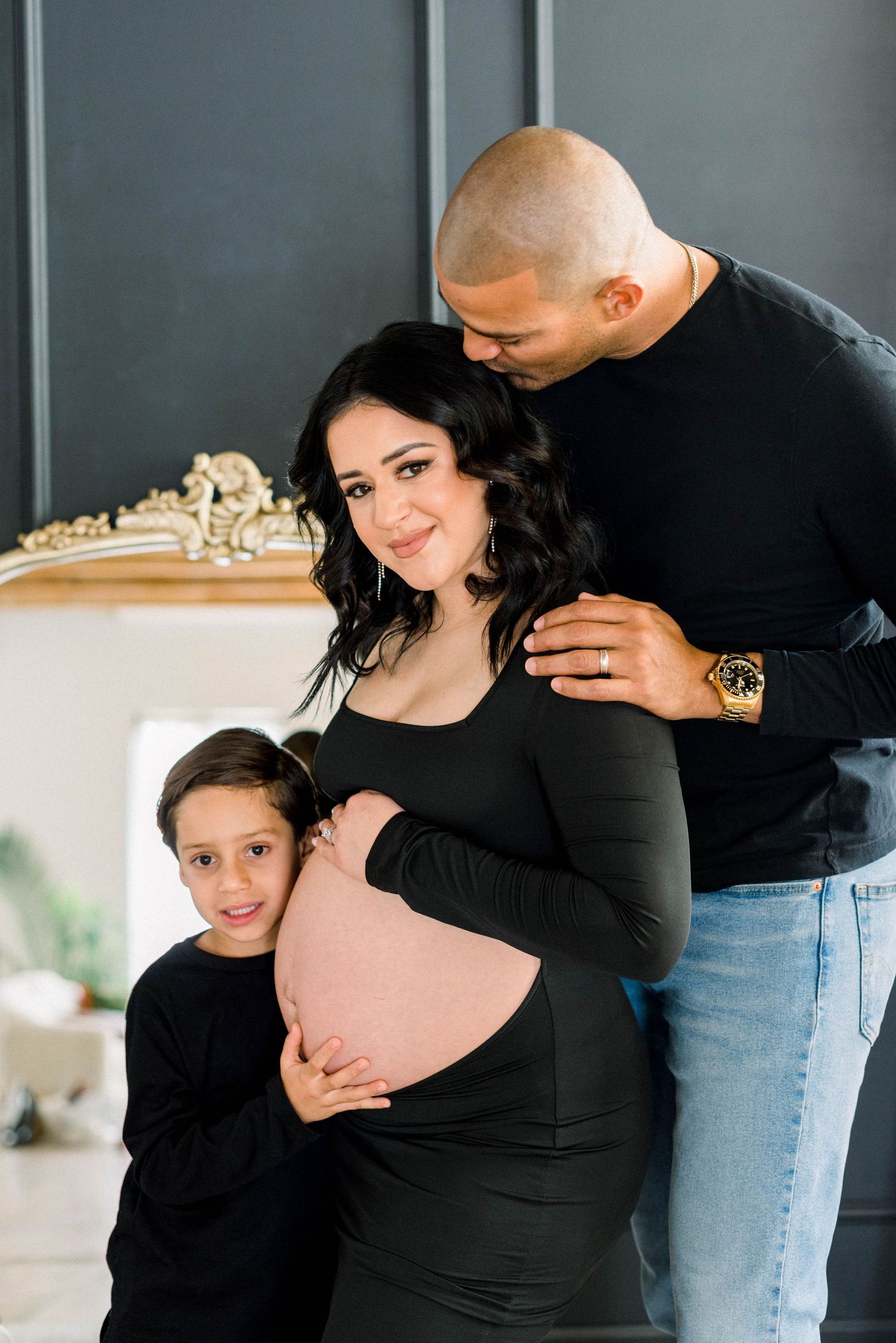 Indoor family maternity photo against ornate mirror backdrop.