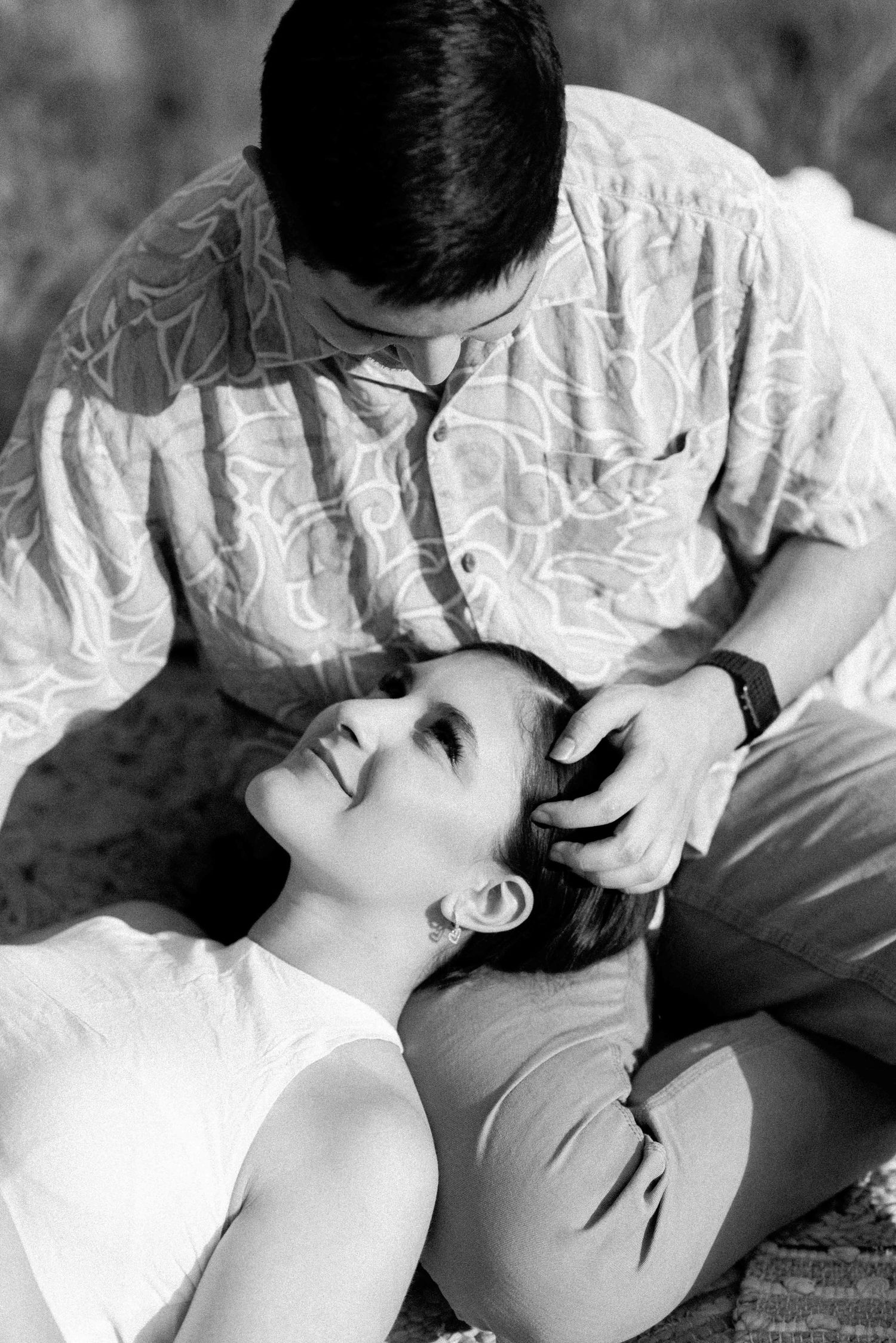 Black and white romantic portrait of a couple sharing an intimate moment on a blanket.