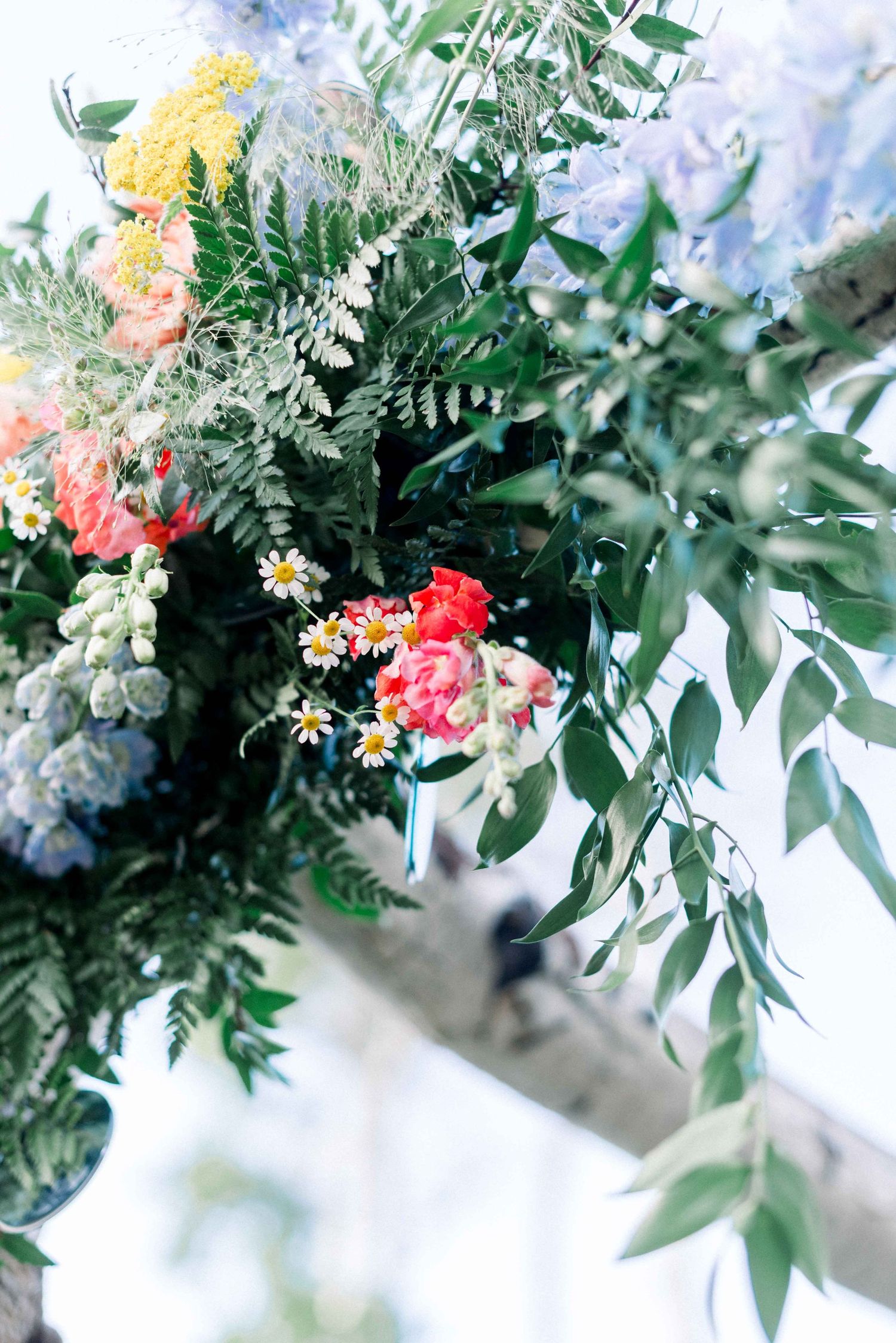 Close-up of elegant wedding floral arrangement with pink and yellow blooms against soft blue background.