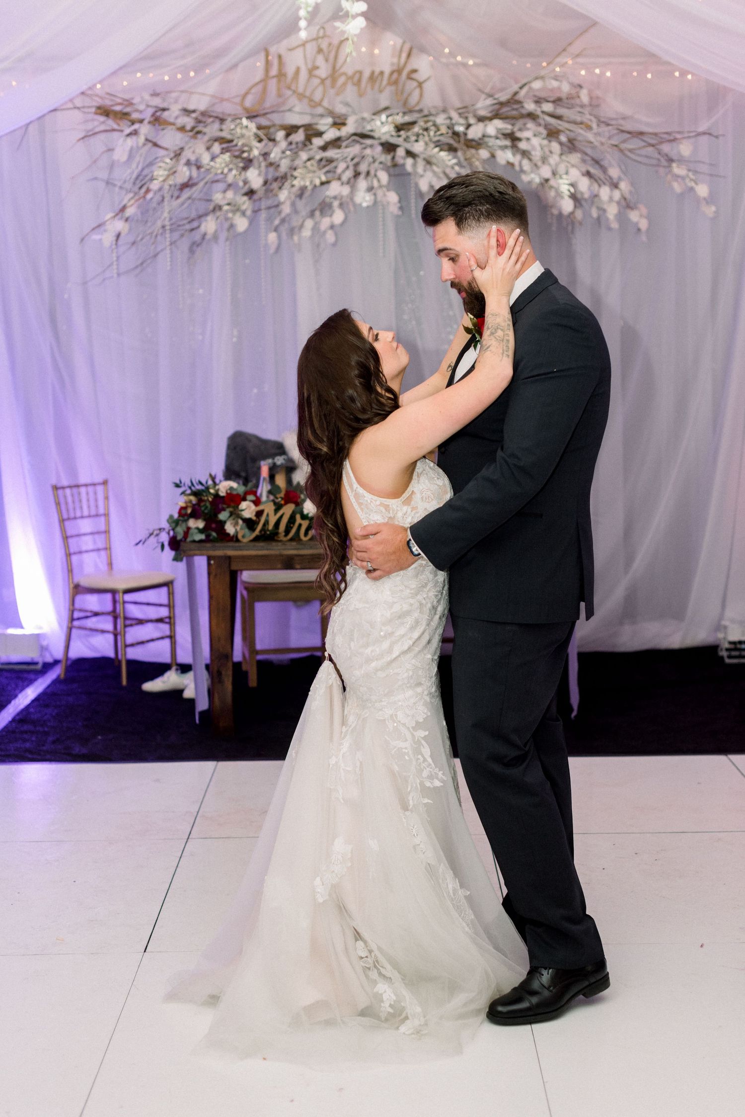 Intimate dance moment between couple under floral installation at wedding reception.