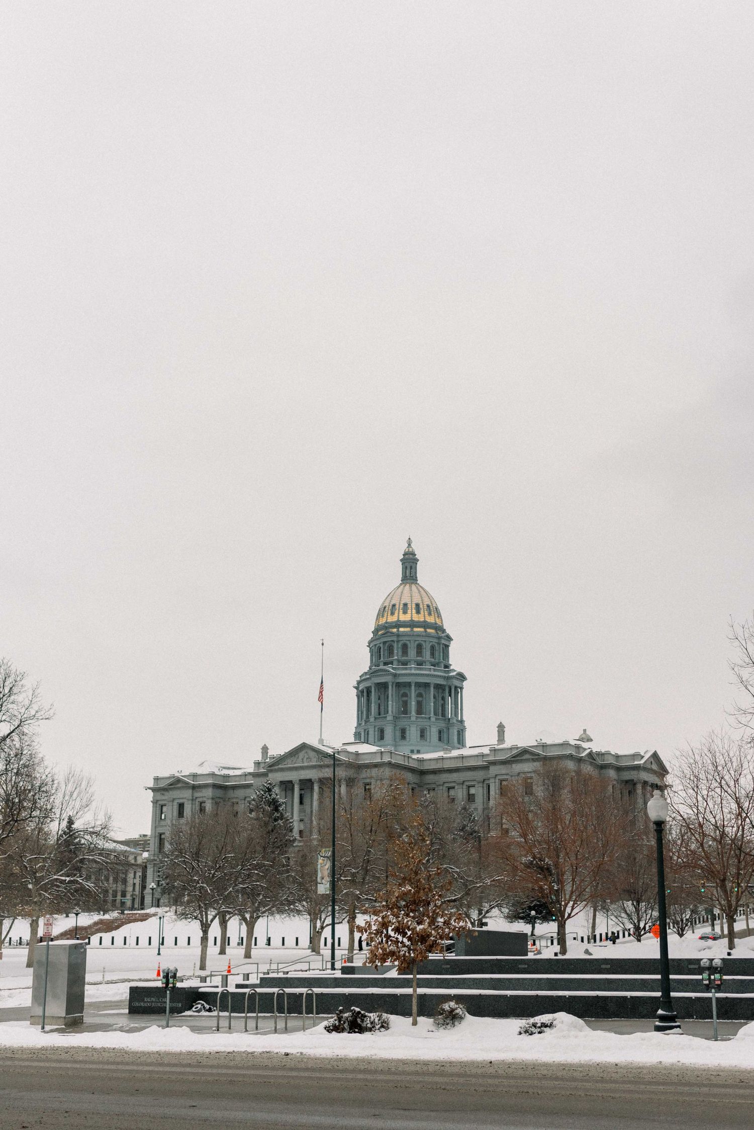 Snow-covered Colorado State Capitol building under overcast winter sky.