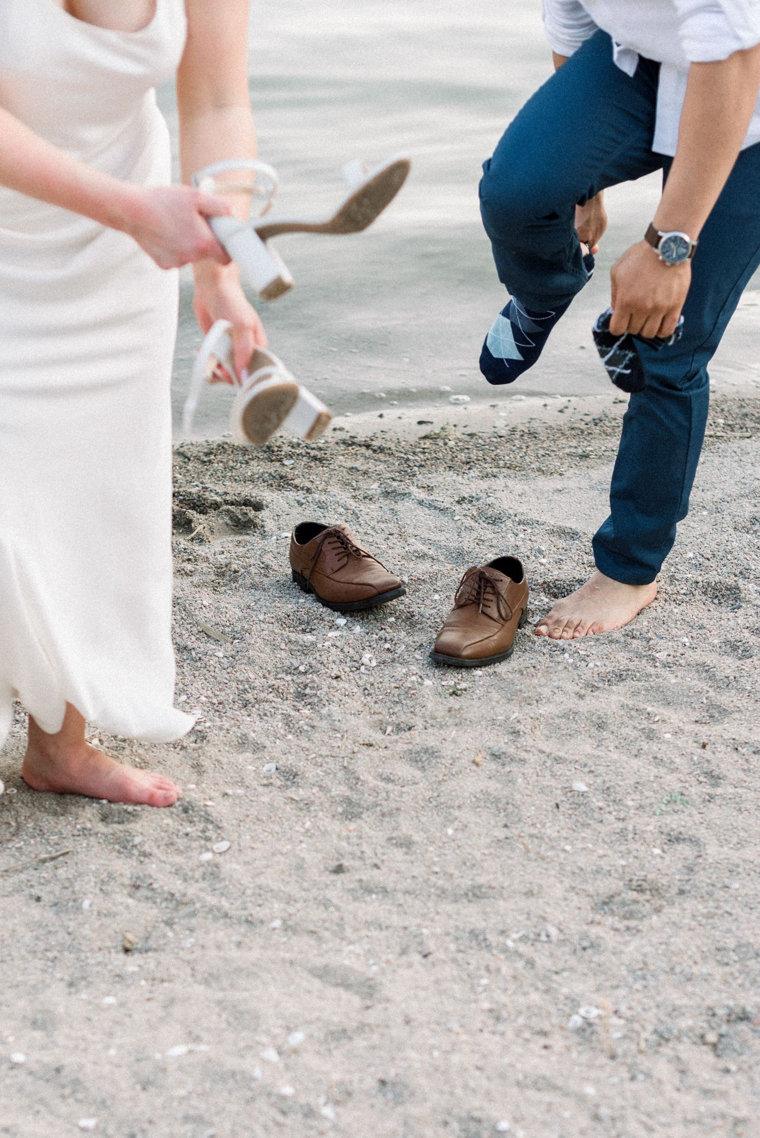 Feet and shoes of people walking on sandy ground.