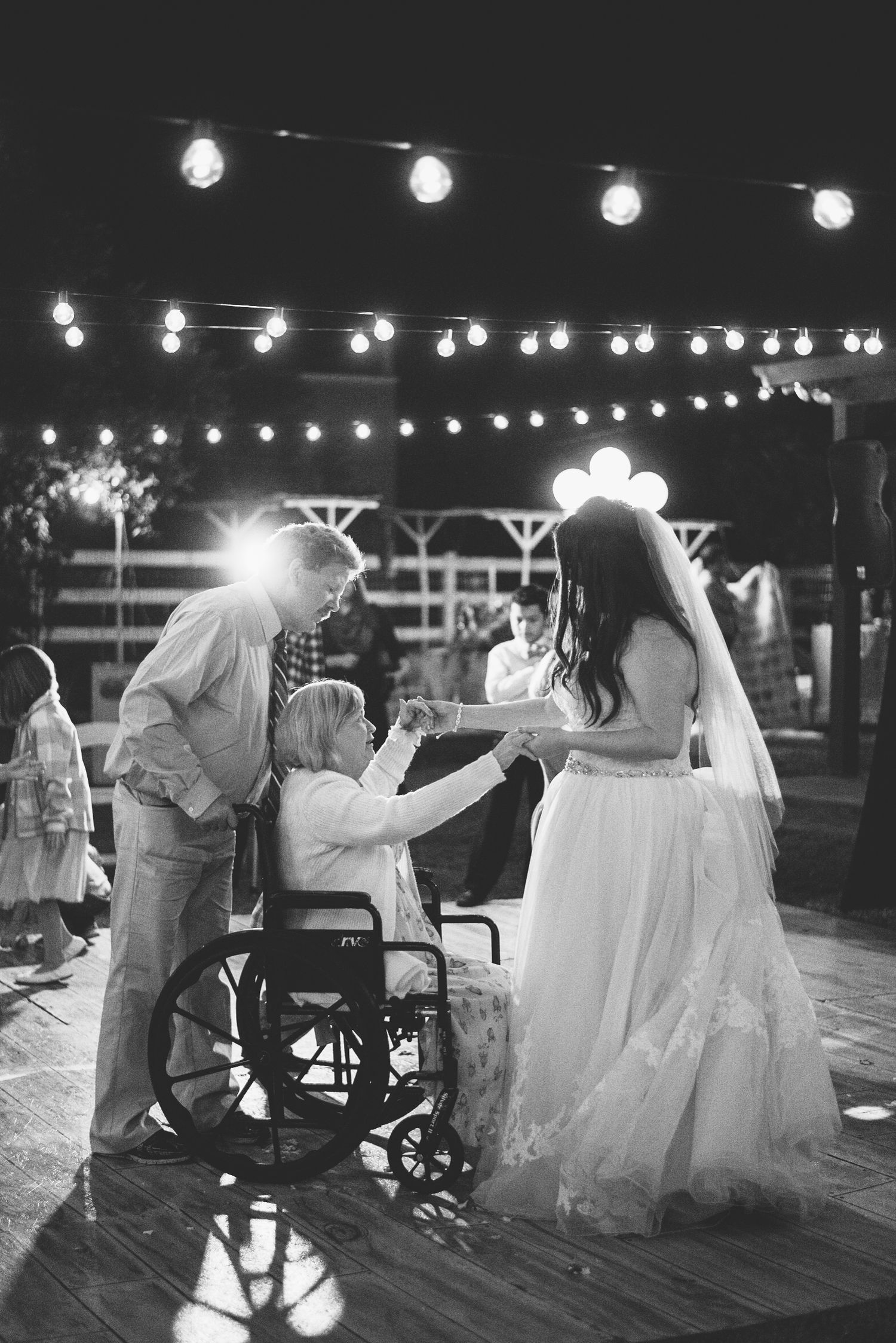 Evening outdoor dance floor with string lights illuminating guests and a wheelchair.
