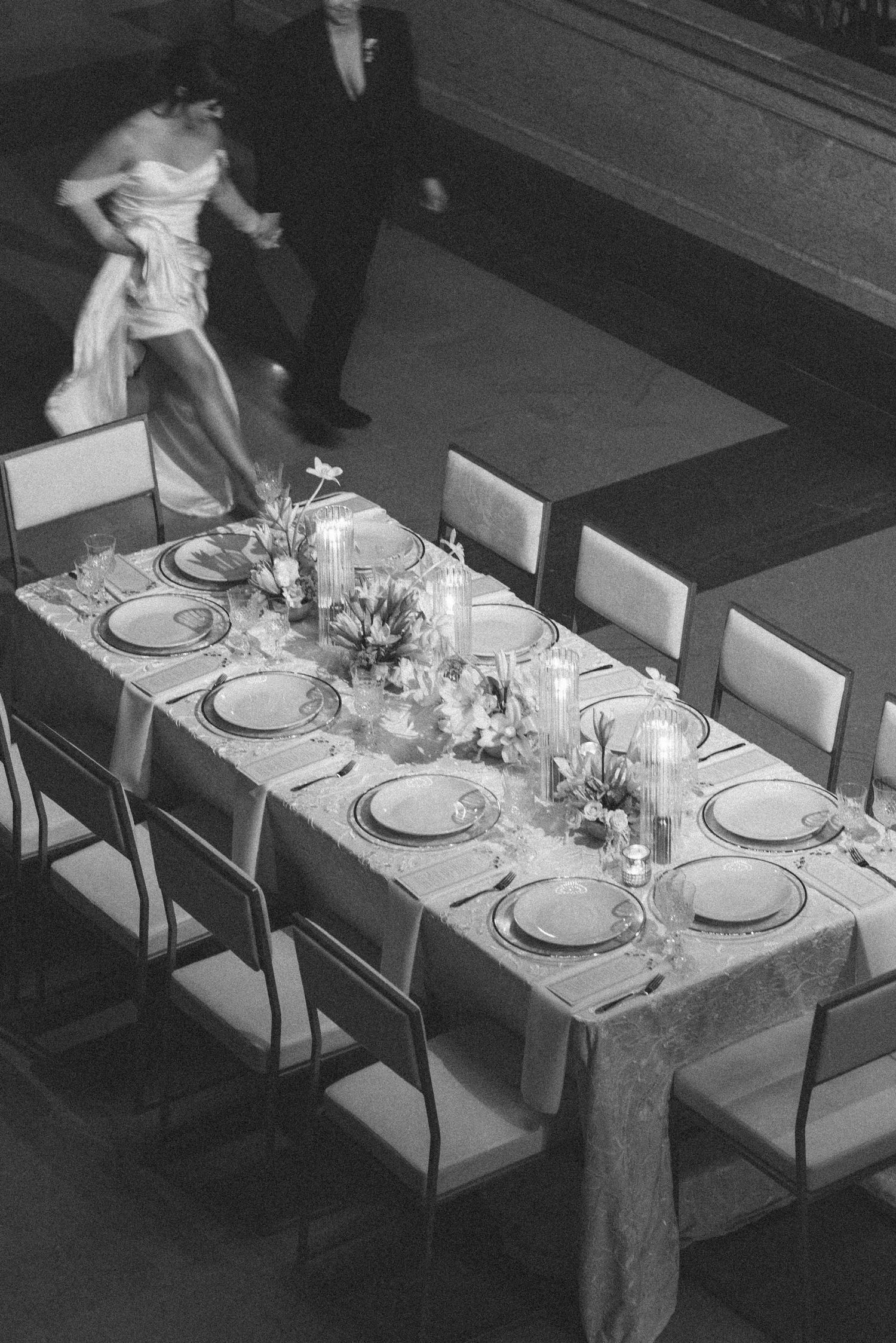 Black and white sequence showing a dining table being set with elegant place settings and white tablecloth.