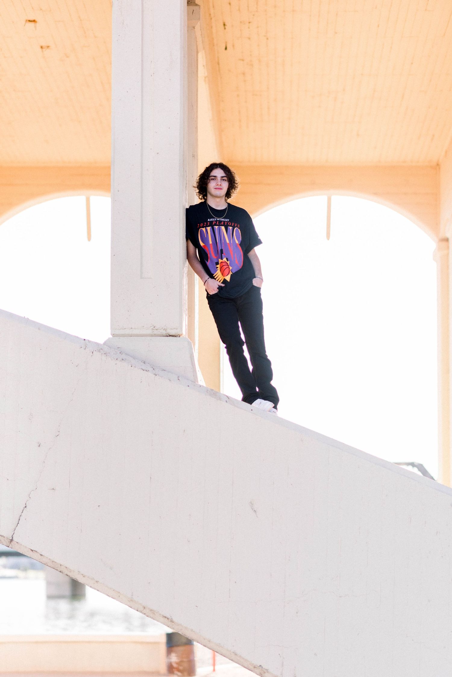 Person in black t-shirt standing on white architectural structure.