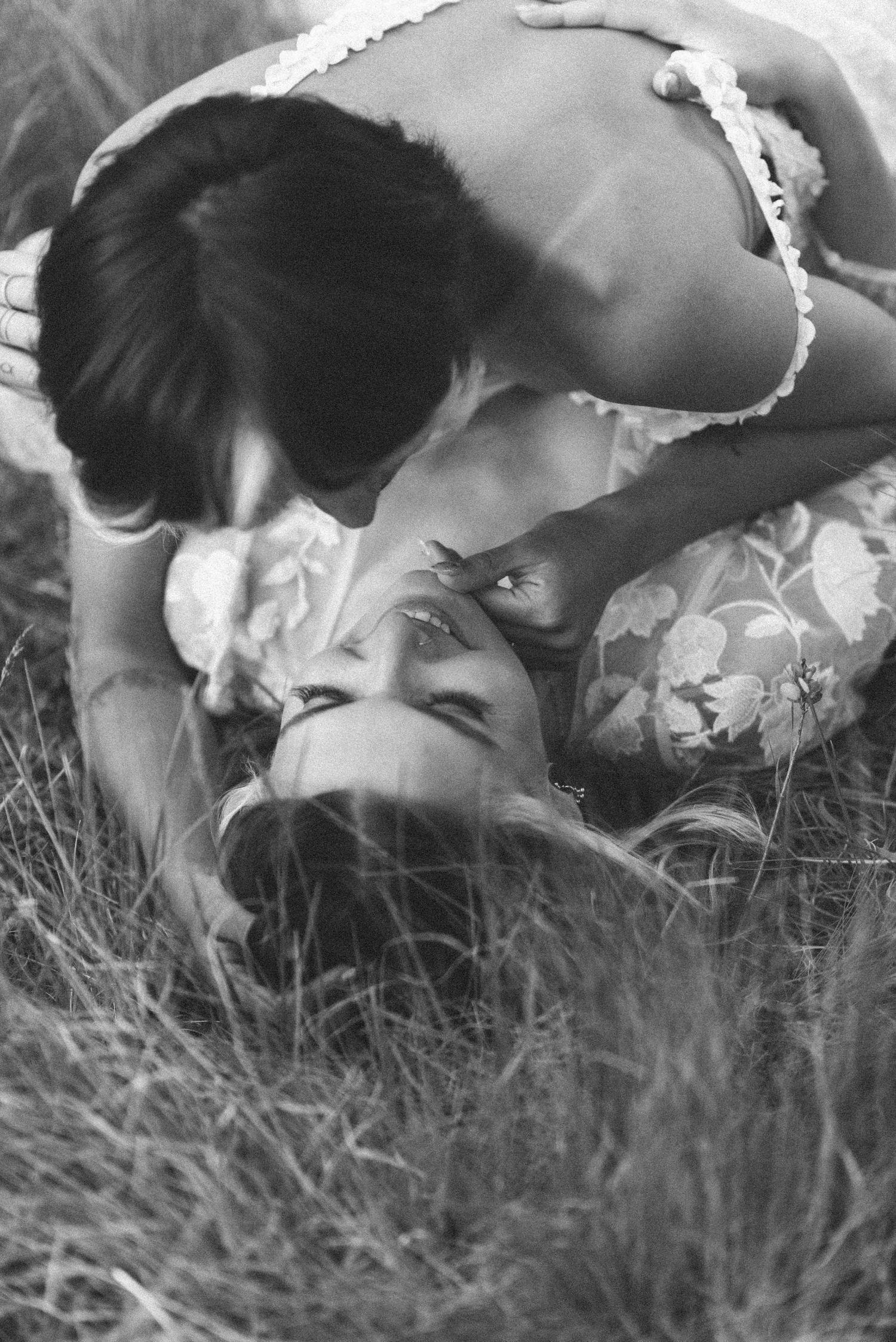 Intimate black and white portrait of couple sharing tender moment in grass.