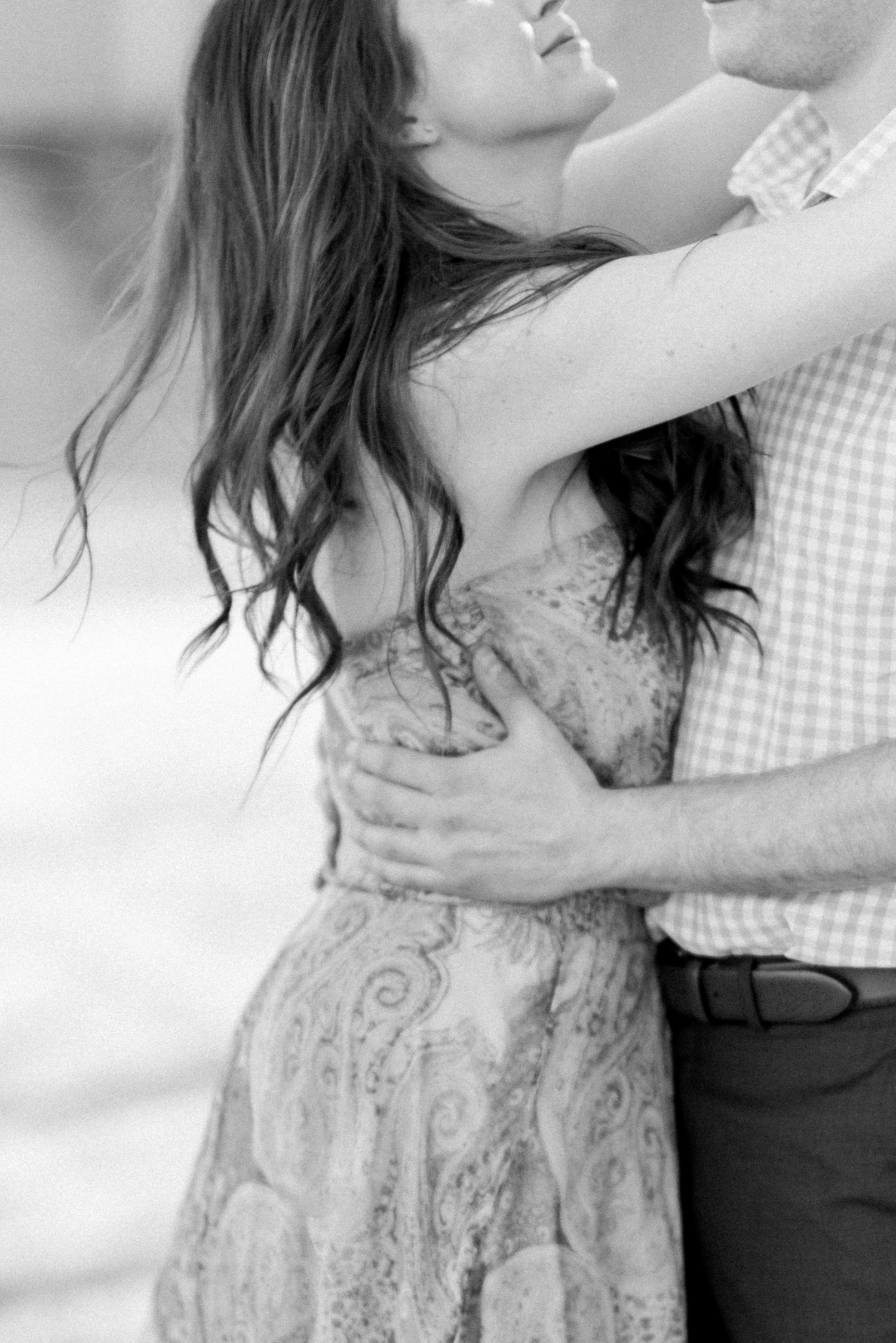 Black and white close-up of romantic couple dancing in elegant attire.