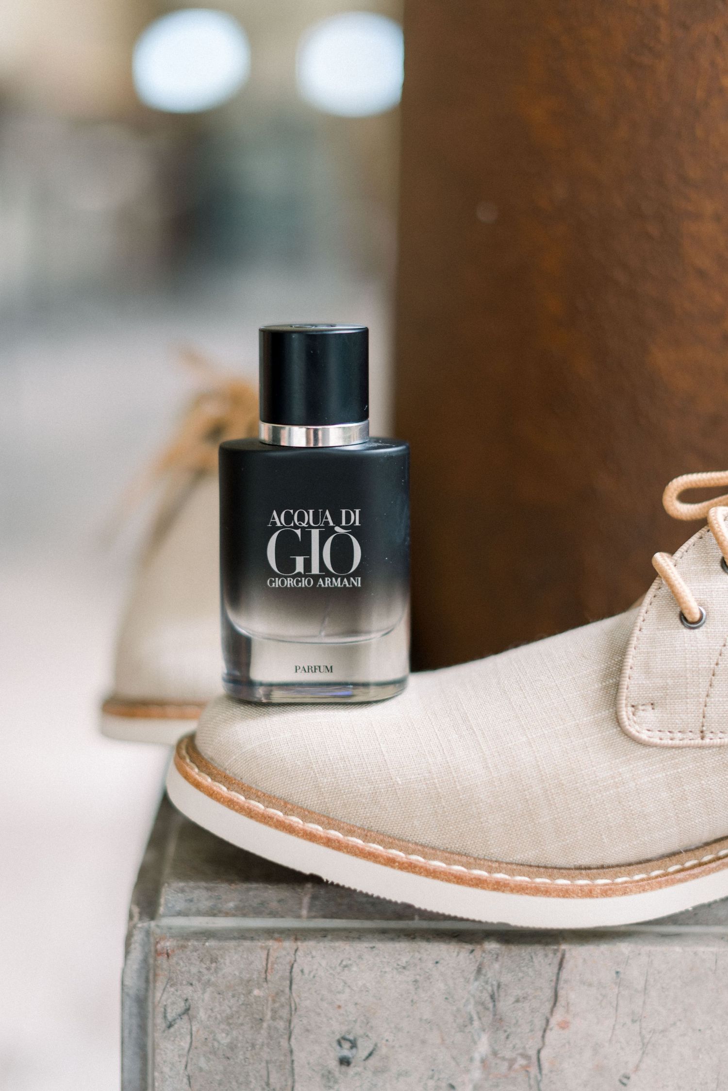 Acqua di Gio cologne bottle placed on a beige suede dress shoe.
