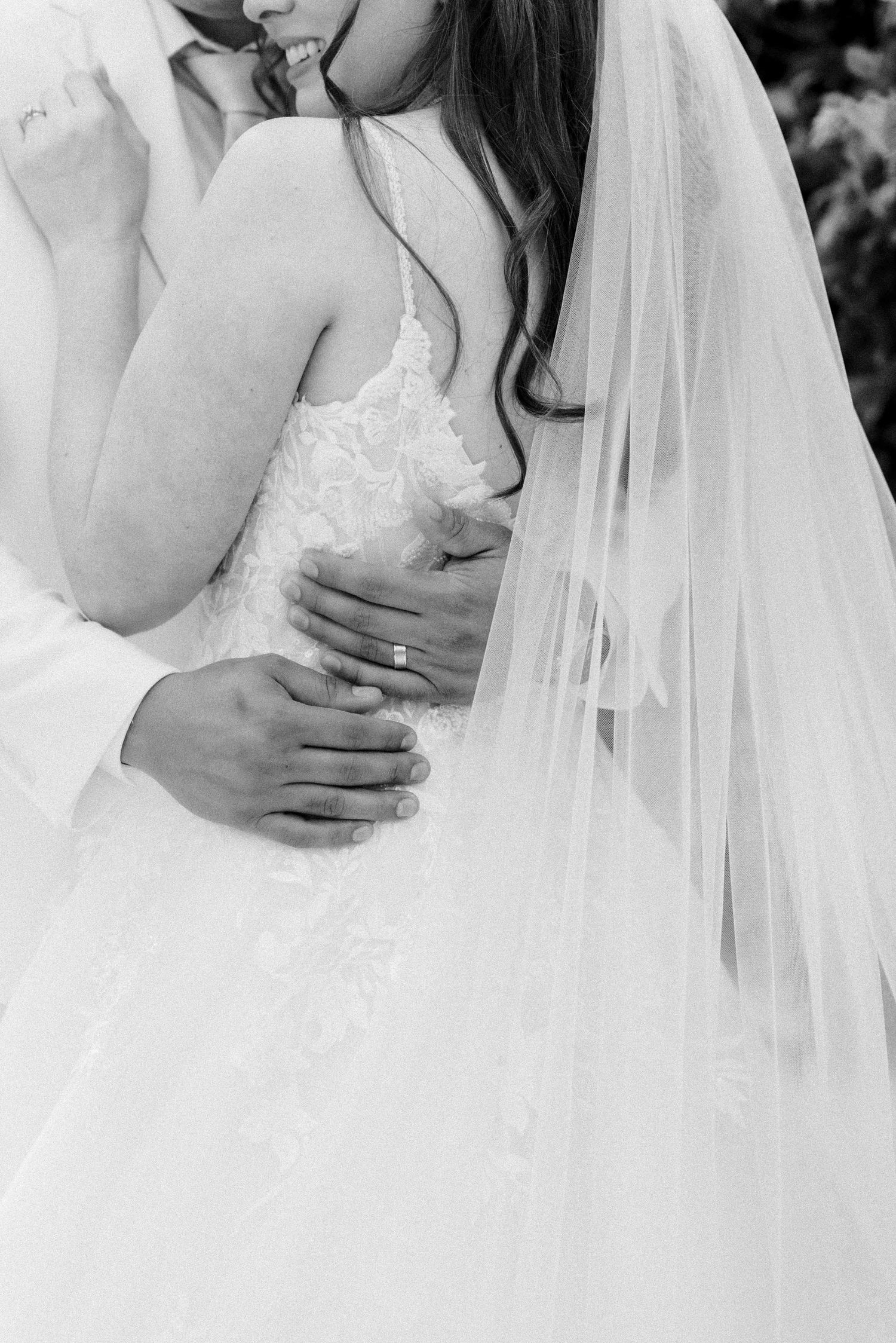 Black and white detail shot of wedding dress bodice with delicate lace and veil.