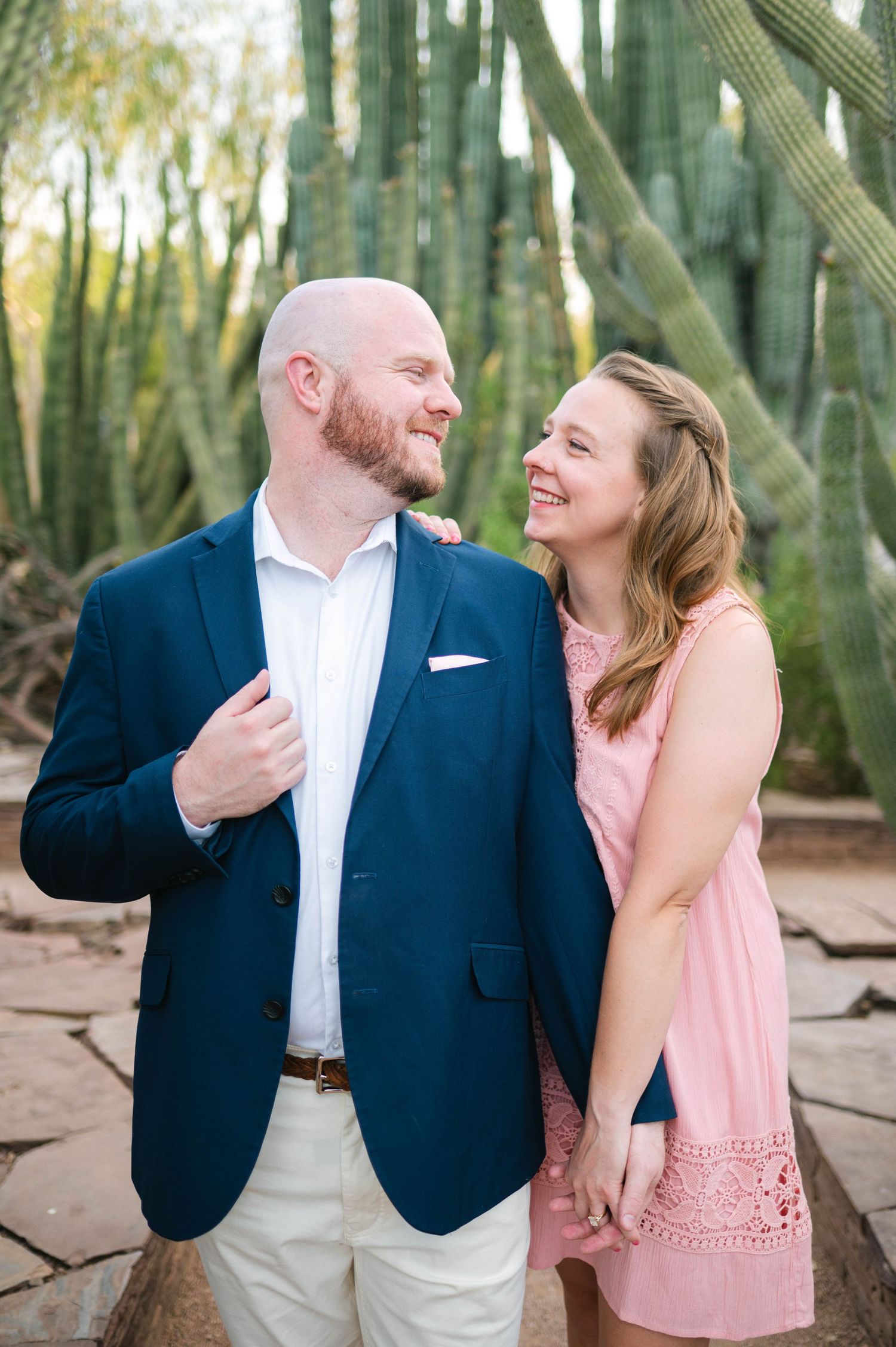 A couple shares a joyful moment together in a bamboo forest wearing coordinated pink and navy outfits.
