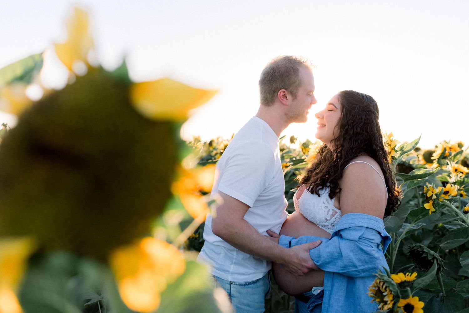 A romantic maternity photo session in a sunflower field at golden hour.