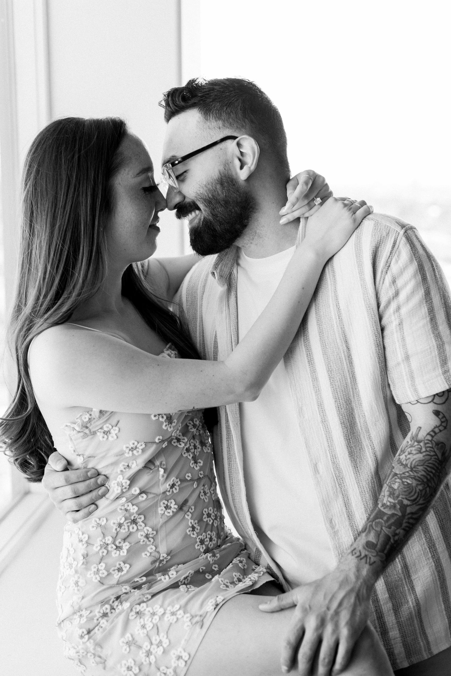 Black and white portrait of a couple embracing in casual formal wear.