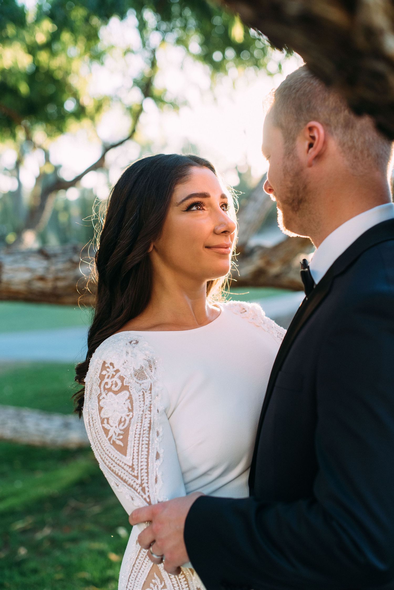 Romantic outdoor portrait with beautiful lace detail on wedding dress visible.