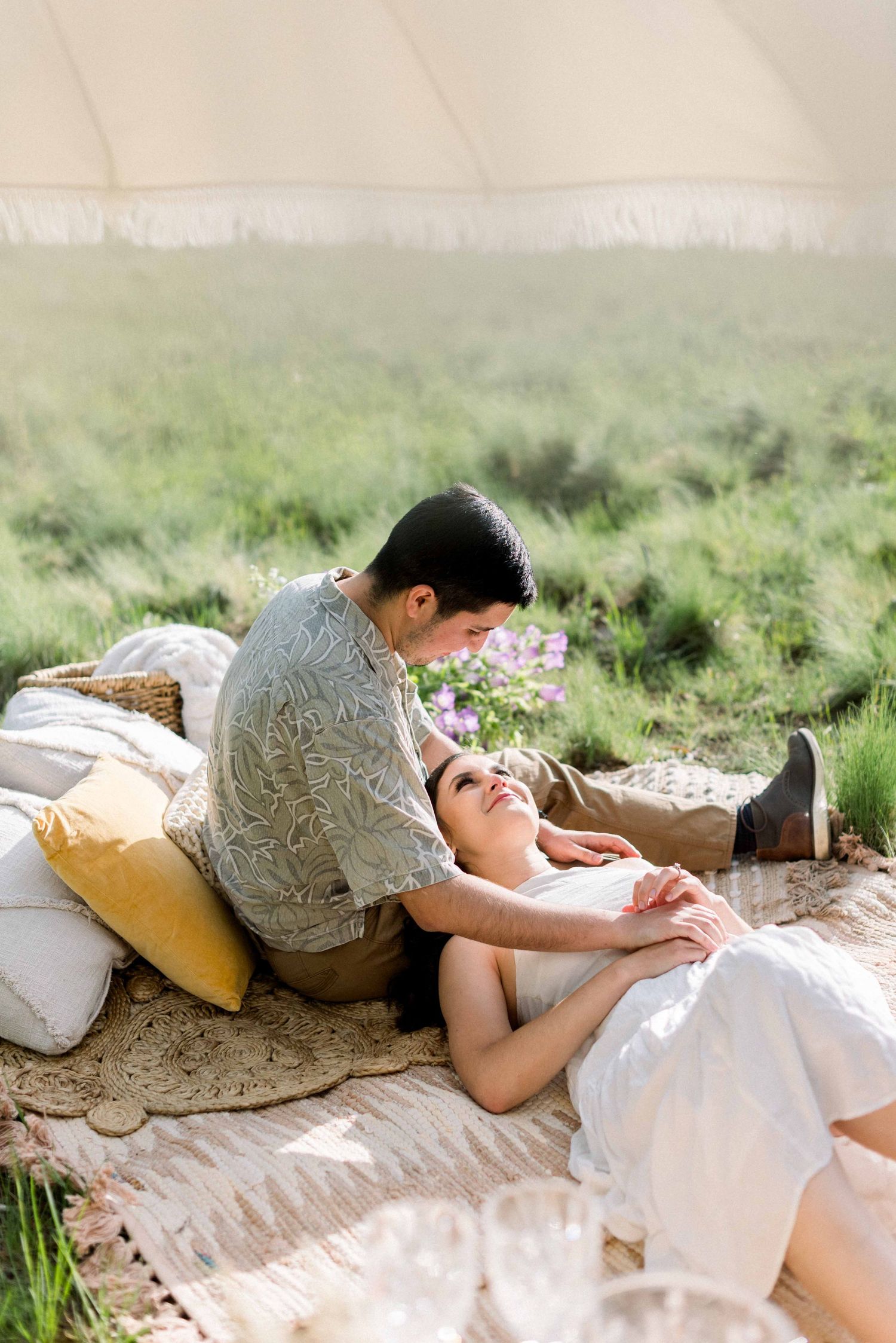 Couple sharing intimate moment on blanket during outdoor photoshoot.