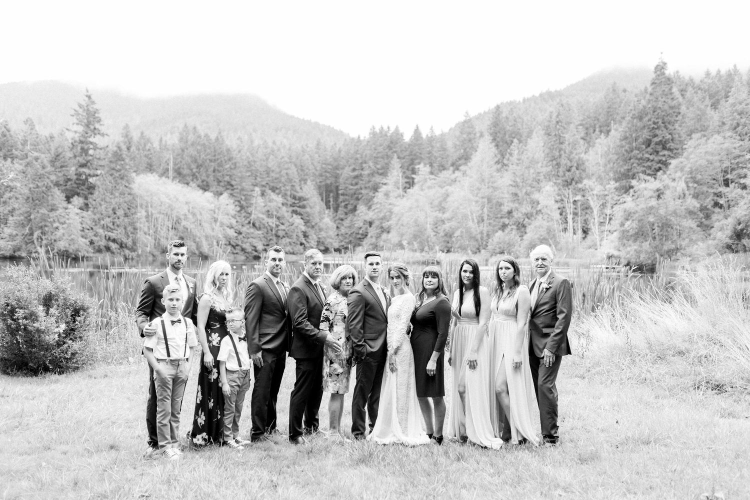 Black and white photo of wedding party lined up in mountain landscape setting.