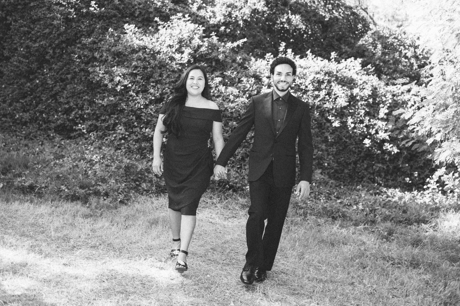 A couple walks together along a grassy path in black and white vintage photograph.