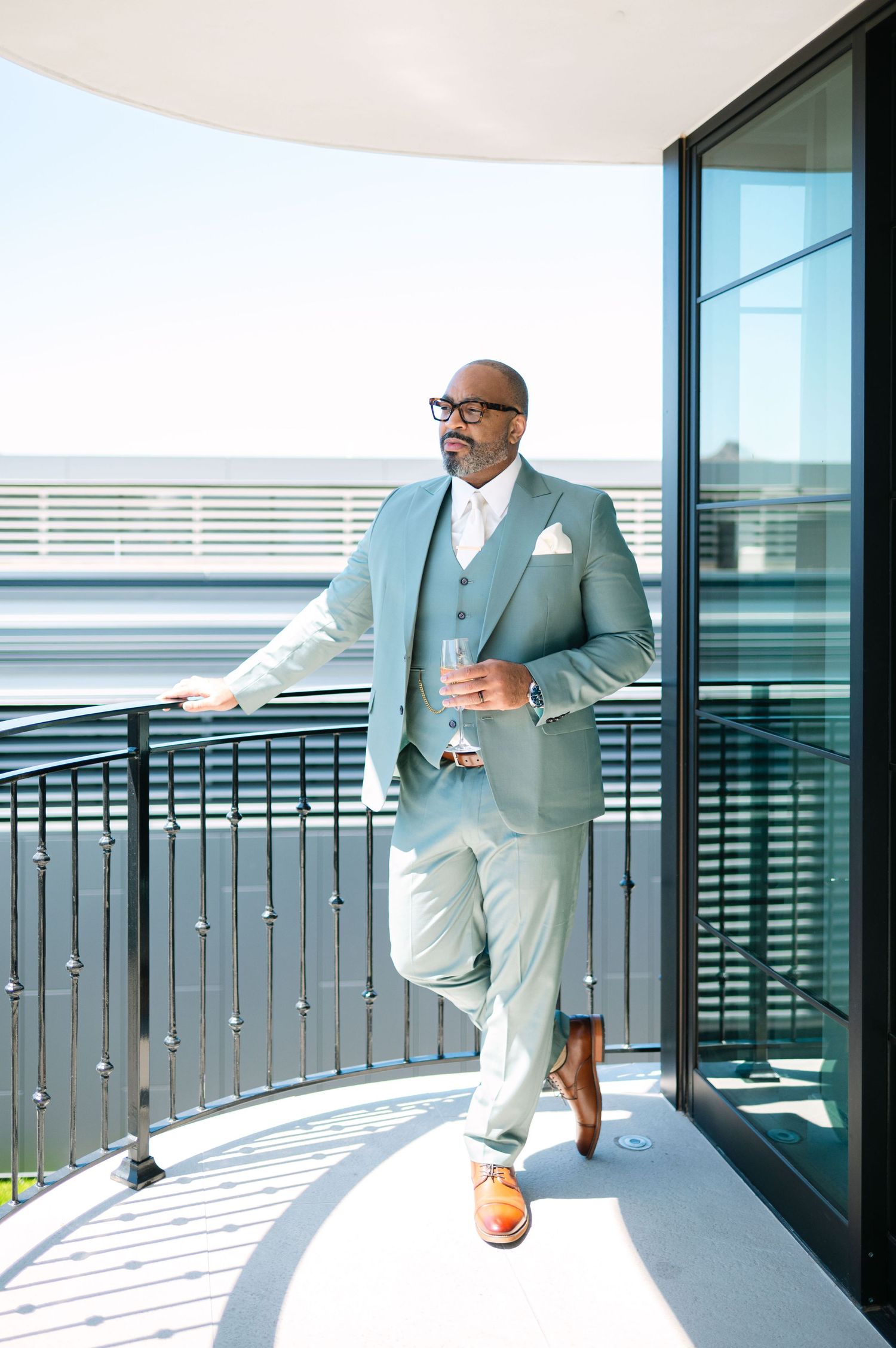Multiple shots of a light gray suit worn on a sunny balcony with modern architectural details.
