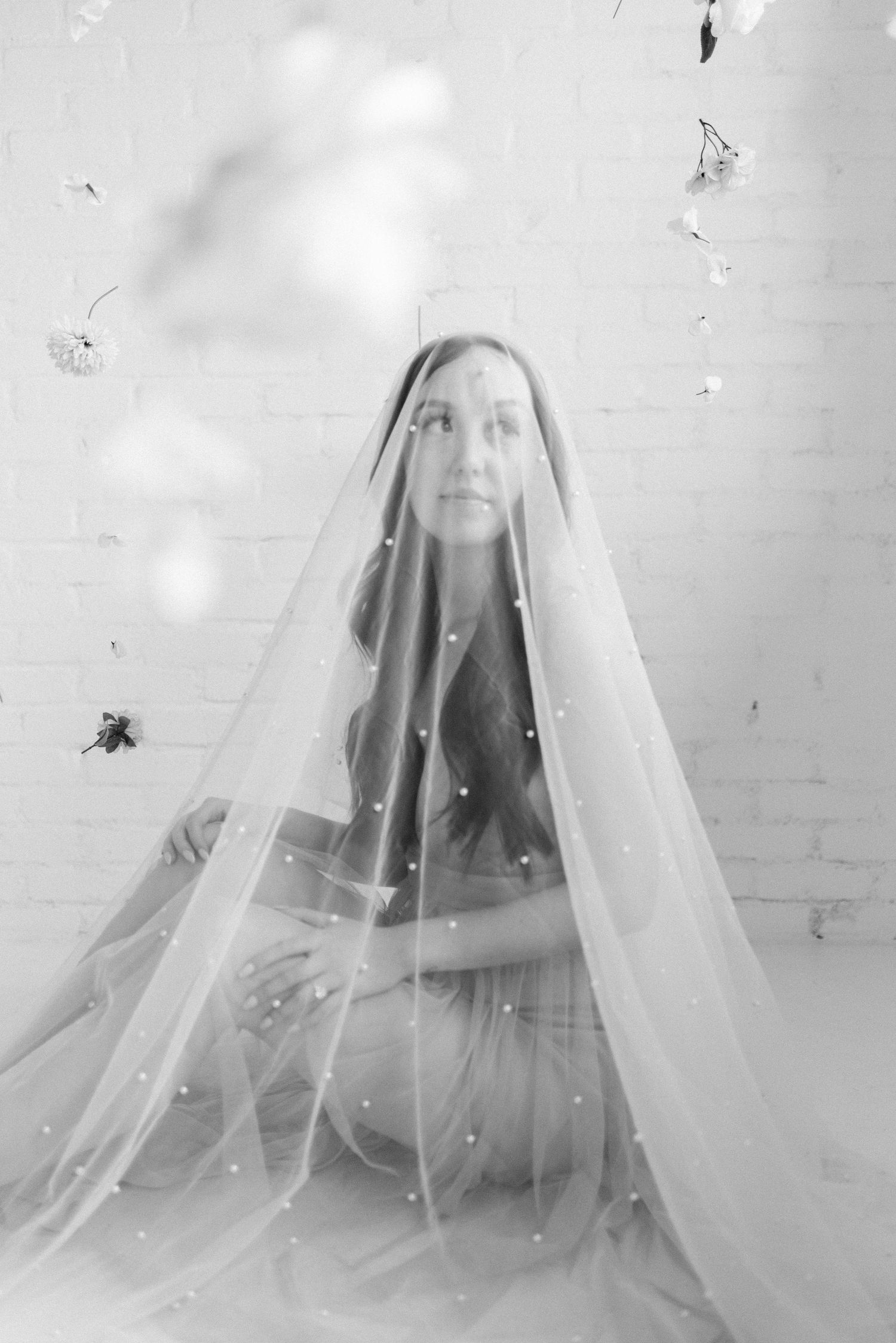 Black and white portrait under sheer veil with soft romantic lighting.