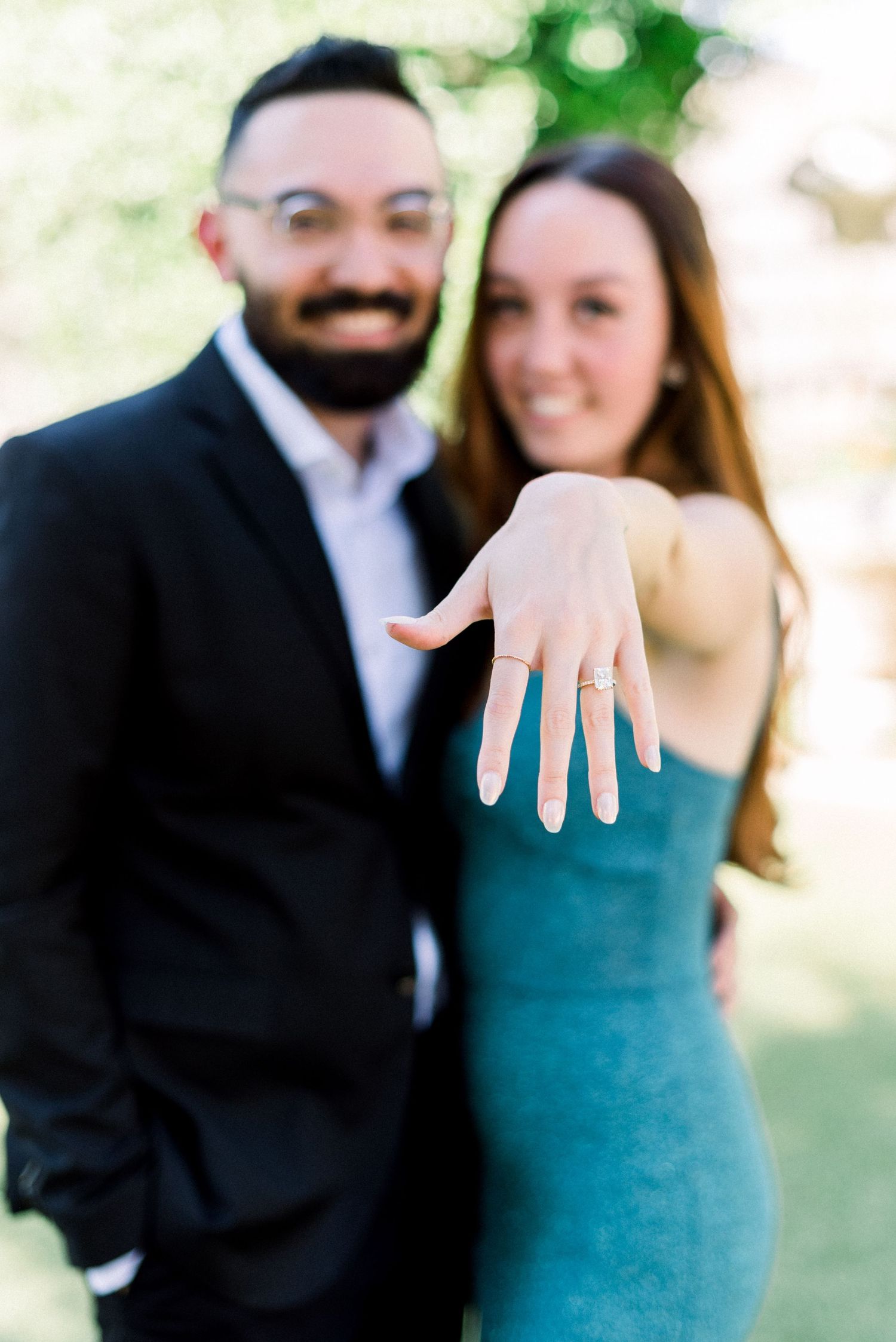 A newly engaged couple showing off the ring with joyful smiles.