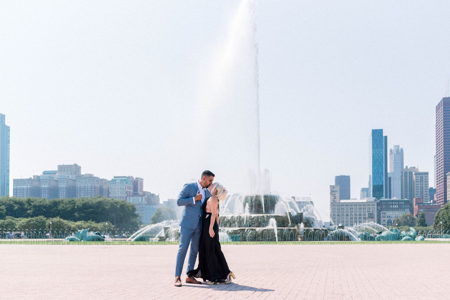 Couple sharing romantic moment by Buckingham Fountain with Chicago skyline behind them.