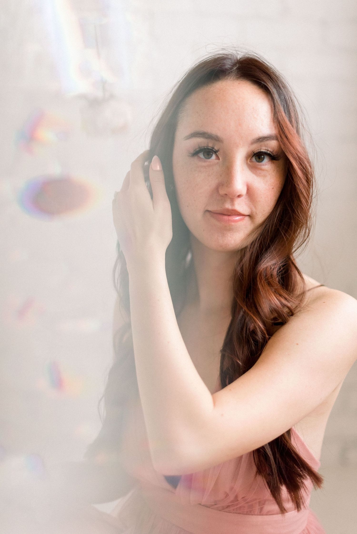 Soft portrait with rainbow prism effects and delicate pink tones.