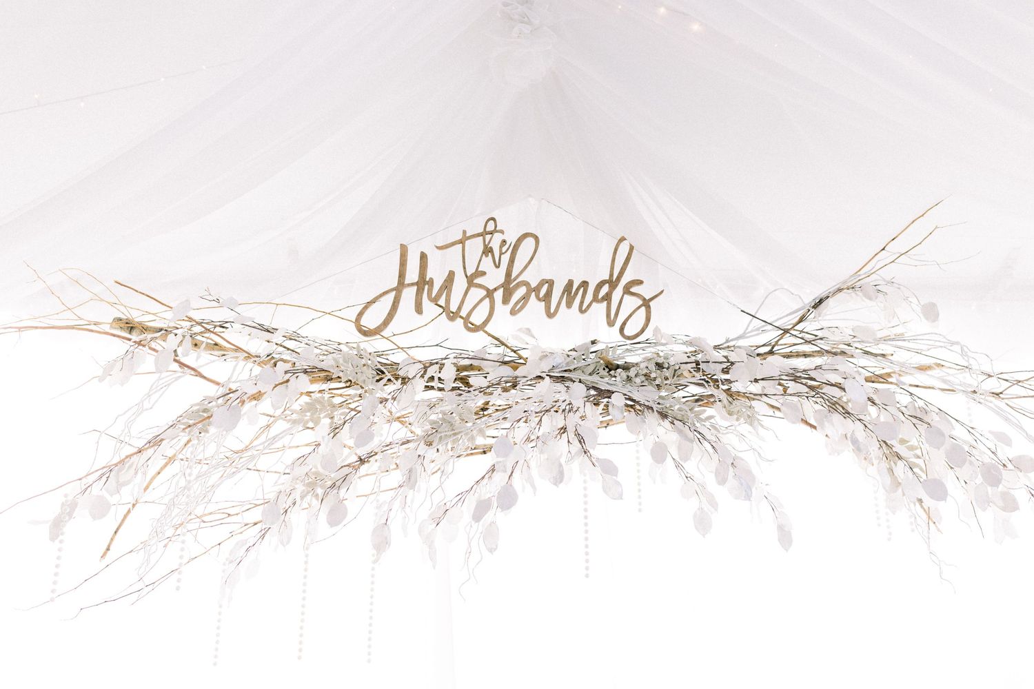 Decorative 'Husbands' sign with dried floral arrangements on white background.