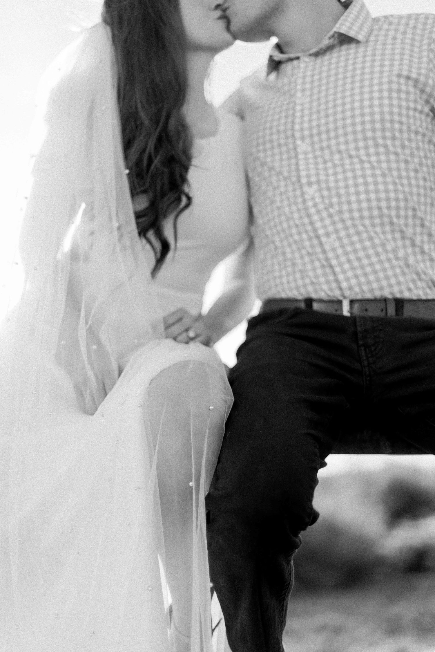 Black and white intimate portrait showing gingham shirt and flowing white dress details.