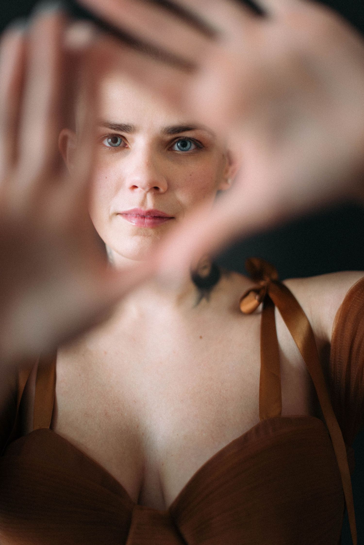 An artistic portrait through hands creating a frame effect.