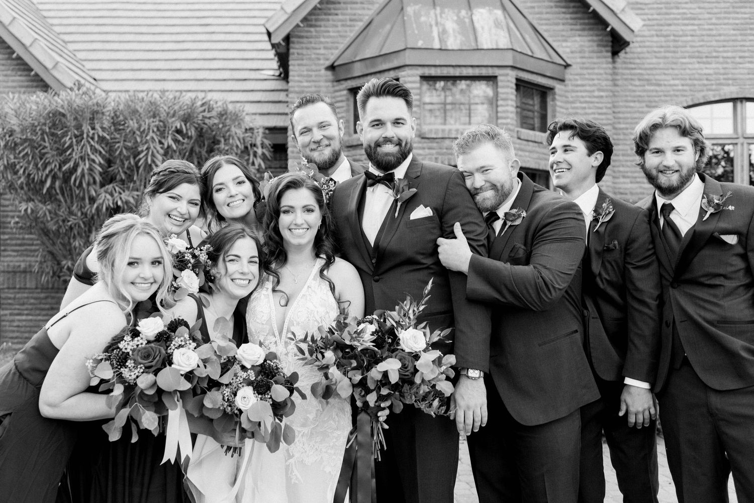 Black and white group photo of wedding party members enjoying candid moment together.