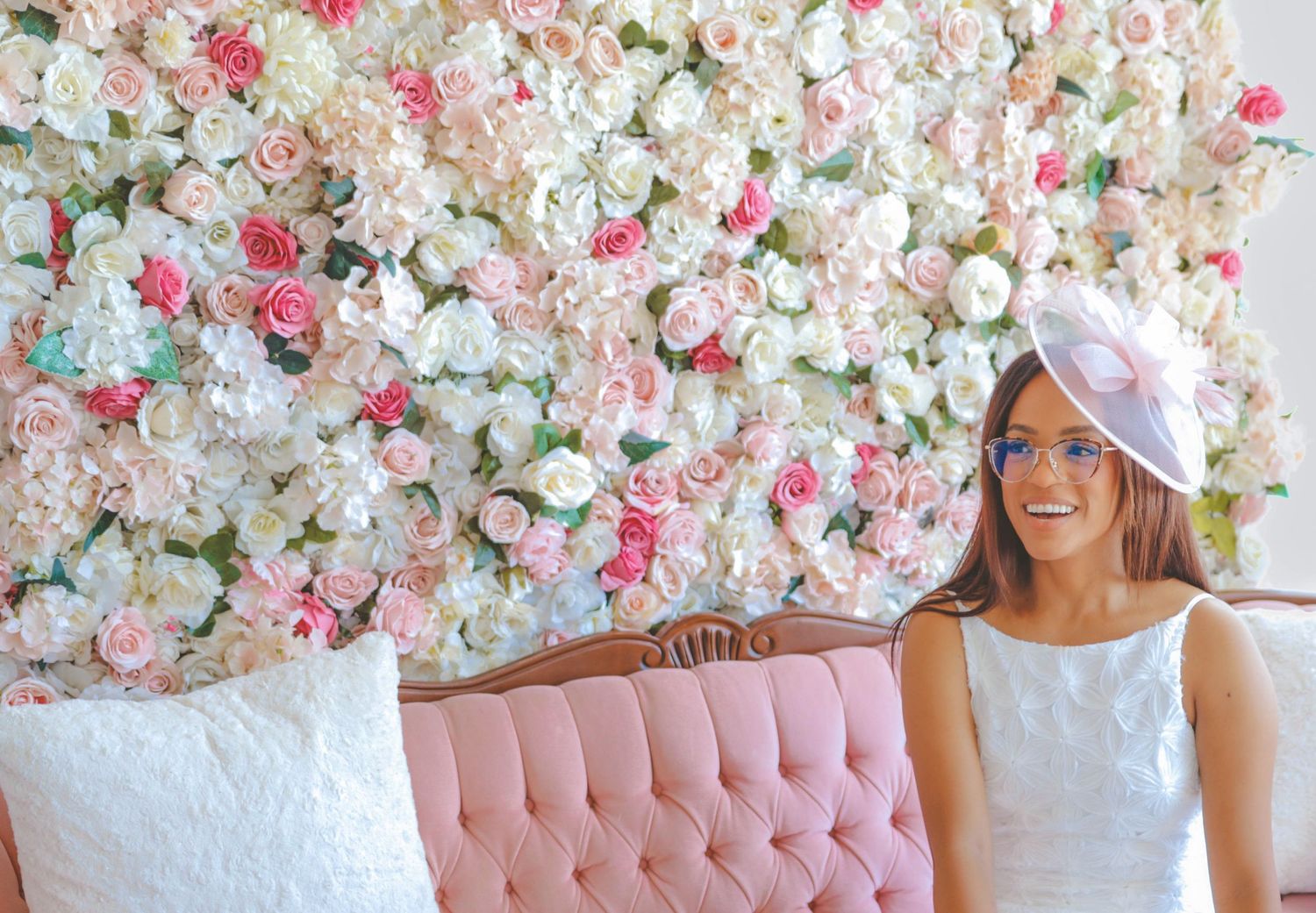 Woman seated on a pink couch in front of a floral backdrop at a bridal shower, captured by a Calgary event photographer